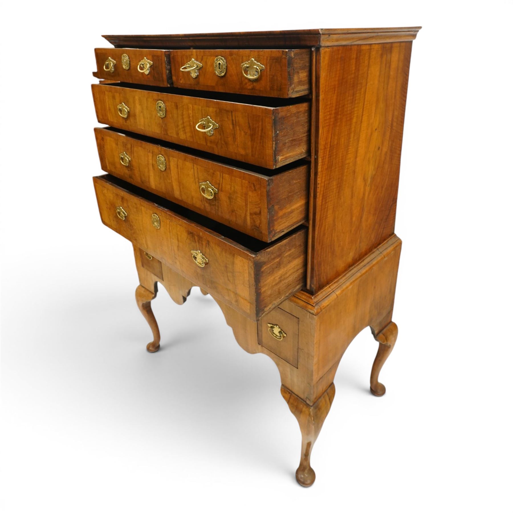 George II figured walnut chest-on-stand, the moulded cavetto top over two short and three long graduating cross-banded drawers, each fitted with pressed brass handle plates, the base fitted with three further drawers over a shaped apron, raised on cabriole supports with pad feet