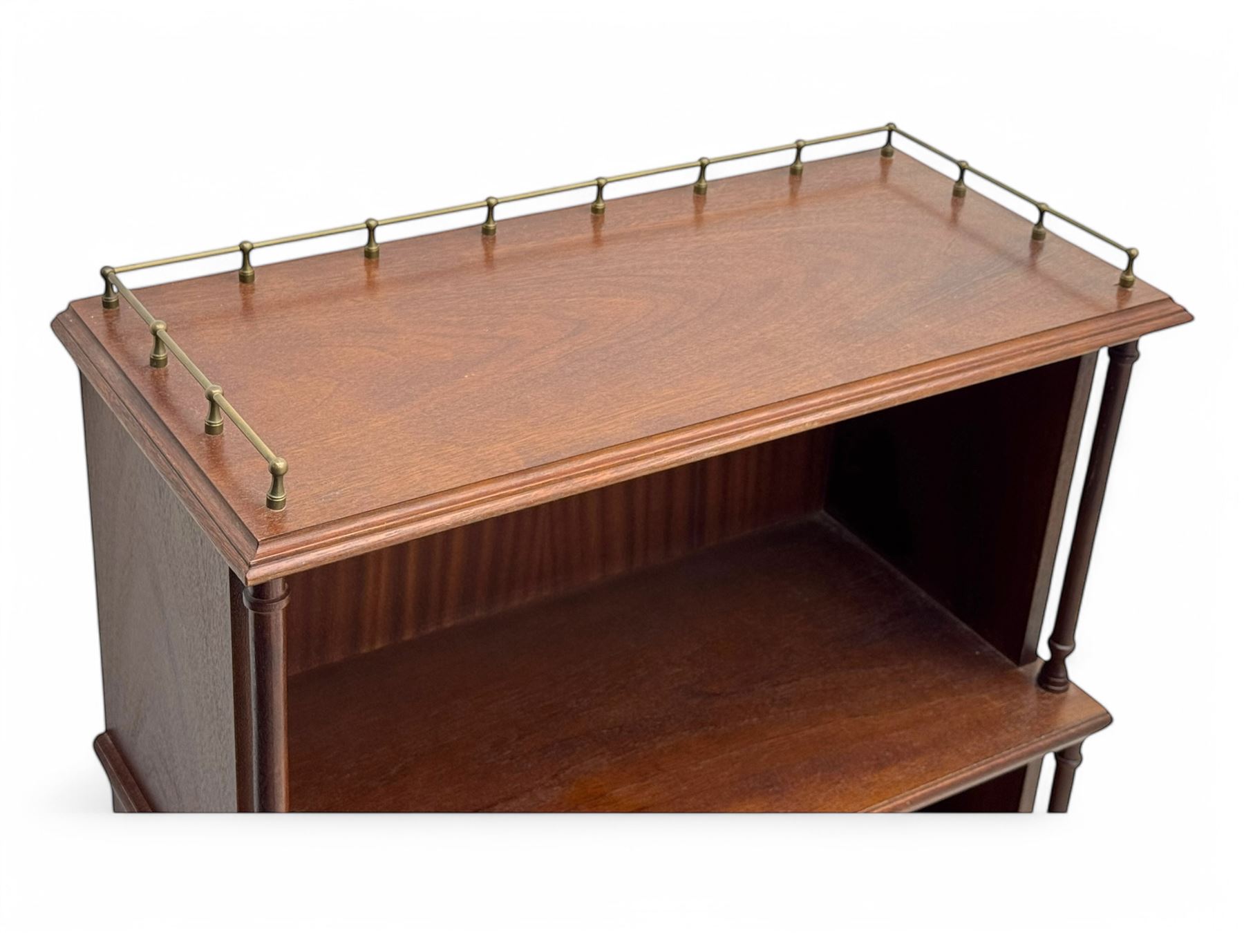 Mid-20th century mahogany open bookshelf, the rectangular top with a brass balustrade gallery, over three shelves each supported by turned column uprights, on shaped apron base