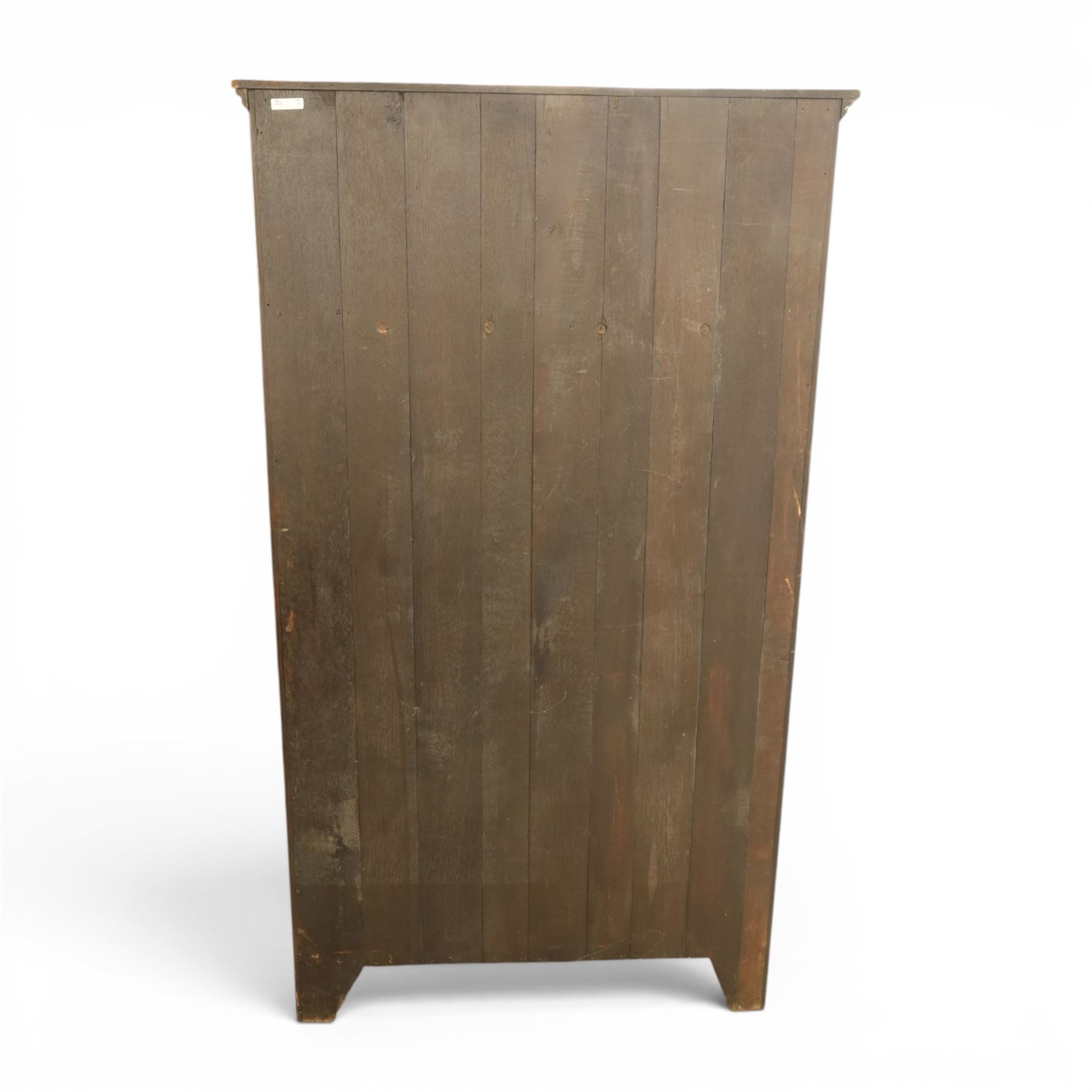 20th century dark stained oak hall robe, cantered sides enclosing a hooks and a shelf, panelled and carved sides, raised on stile supports