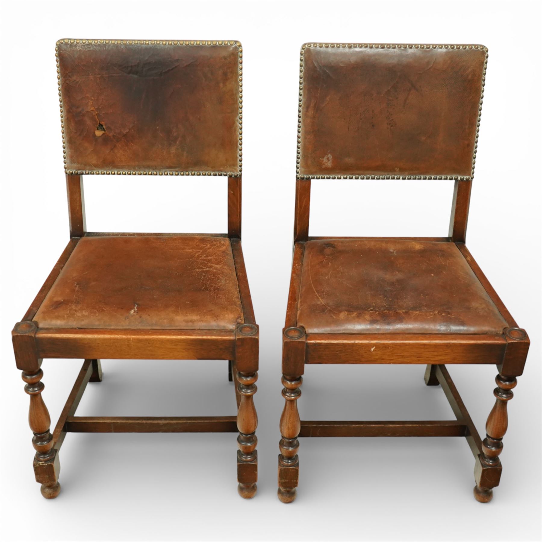 Early 20th century four oak side chairs, with studded leather upholstered backs and seats, on square section legs with baluster turned front supports and straight stretchers
