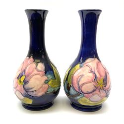 Pair of Moorcroft vases, decorated in the pink Magnolia pattern upon a dark blue ground, each with impressed mark beneath, H16cm.  