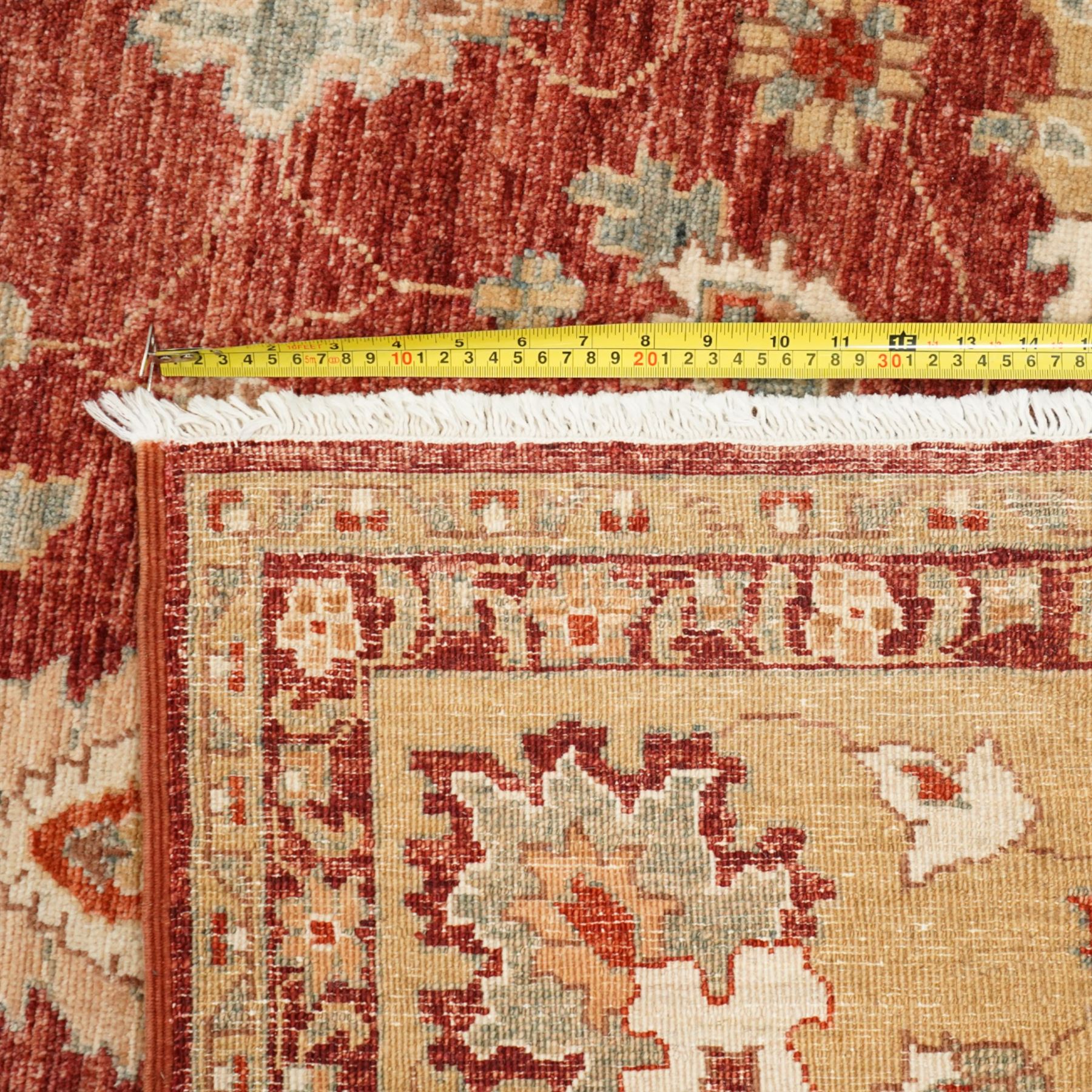 Persian Chubi Oushak style revival hand-knotted carpet, madder red field decorated with large-scale stylized palmettes and floral sprays framed by a broad pale golden border with simplified foliate motifs and multiple guard stripes