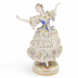 Three Continental lace figures, comprising a figure group modelled as two seated female figures reading, with lace trimmed gowns, H19.5cm, the other two examples modelled female figure with arms outstretched, the lace gowns encrusted with flowers, taller example H21cm