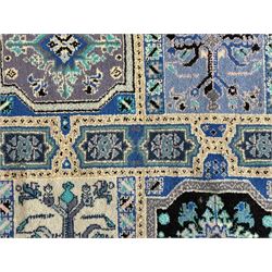 Morrocan single weft blue ground rug, the field segmented into a grid of ten rectangular panels, bordered by a series of guard bands with repeating floral and geometric patterns with interlocking vines and rosettes, the edges finished with a fringe of twisted tassles