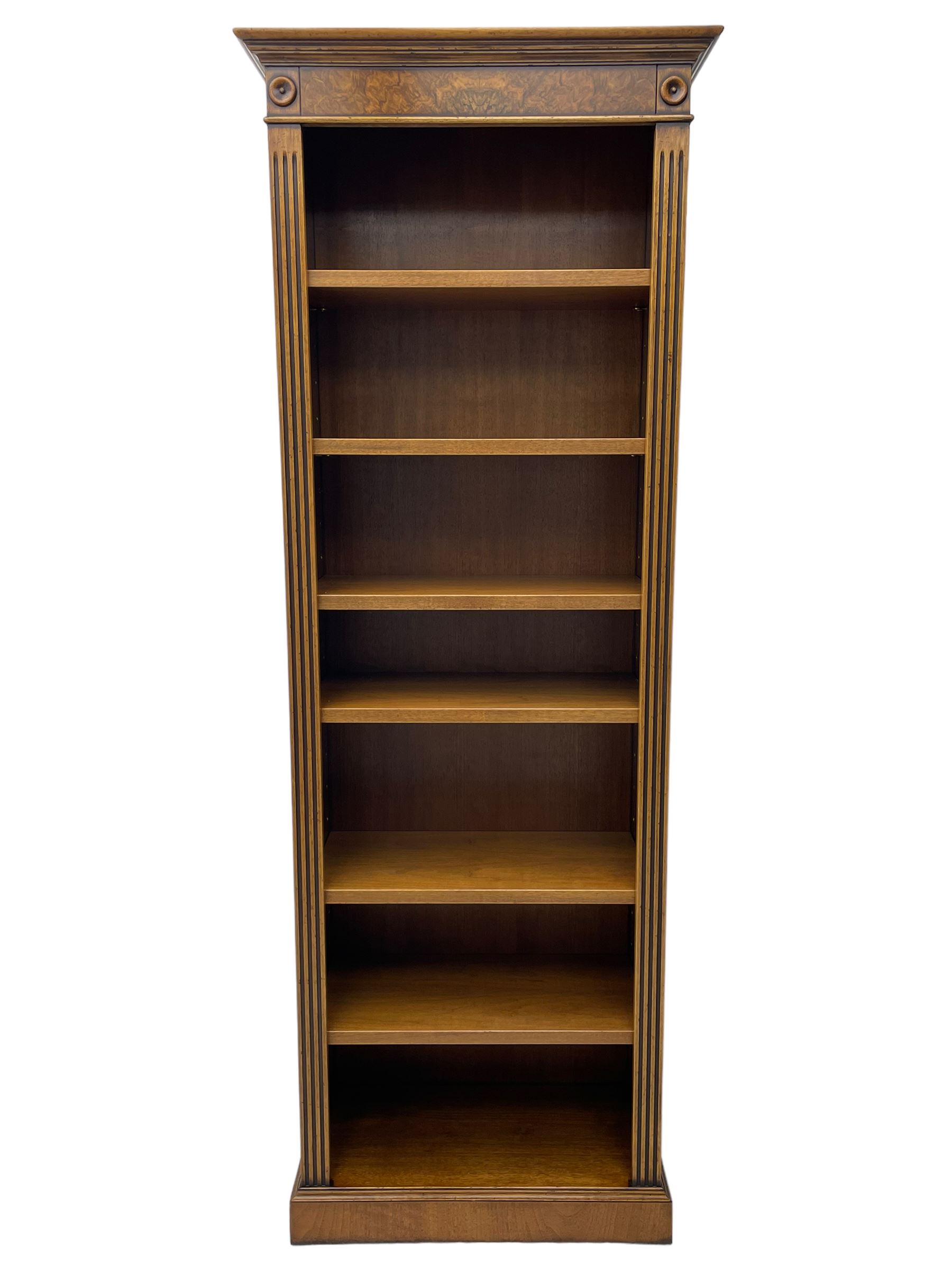 Georgian design walnut open bookcase, projecting cornice over figured banded frieze flanked by roundels, fitted with six adjustable shelves with flanking fluted uprights, on skirted base
