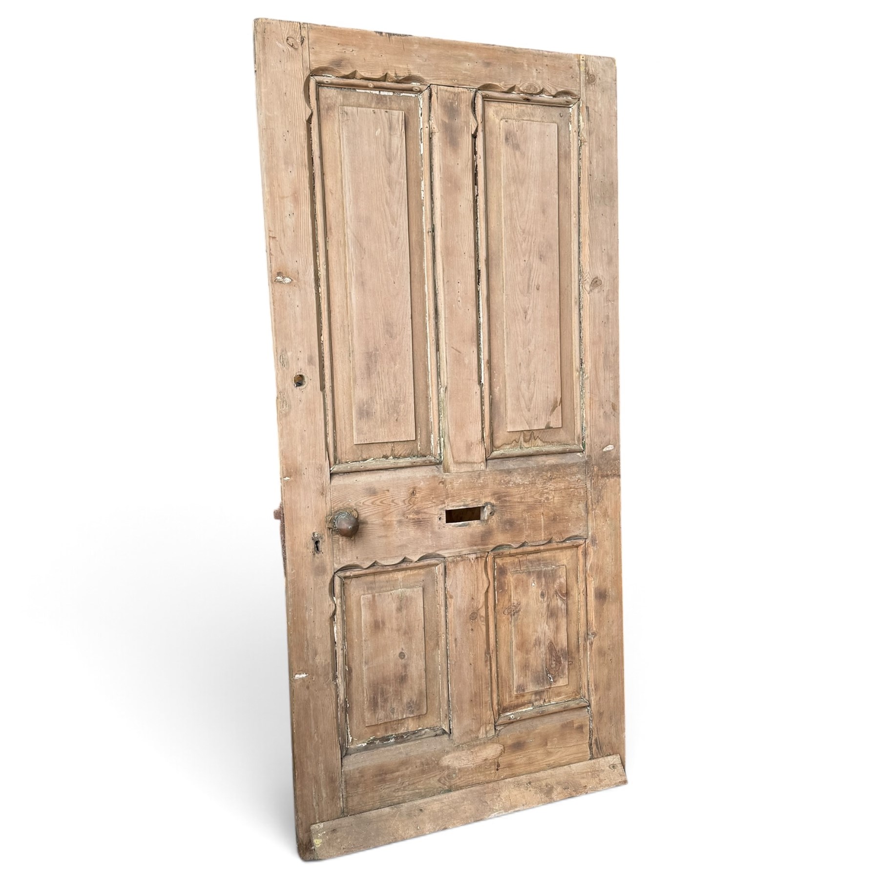 Victorian stripped pine four-panel door, the raised fielded panels within carved foliate and moulded surrounds, with iron lock and fittings and brass knob handle