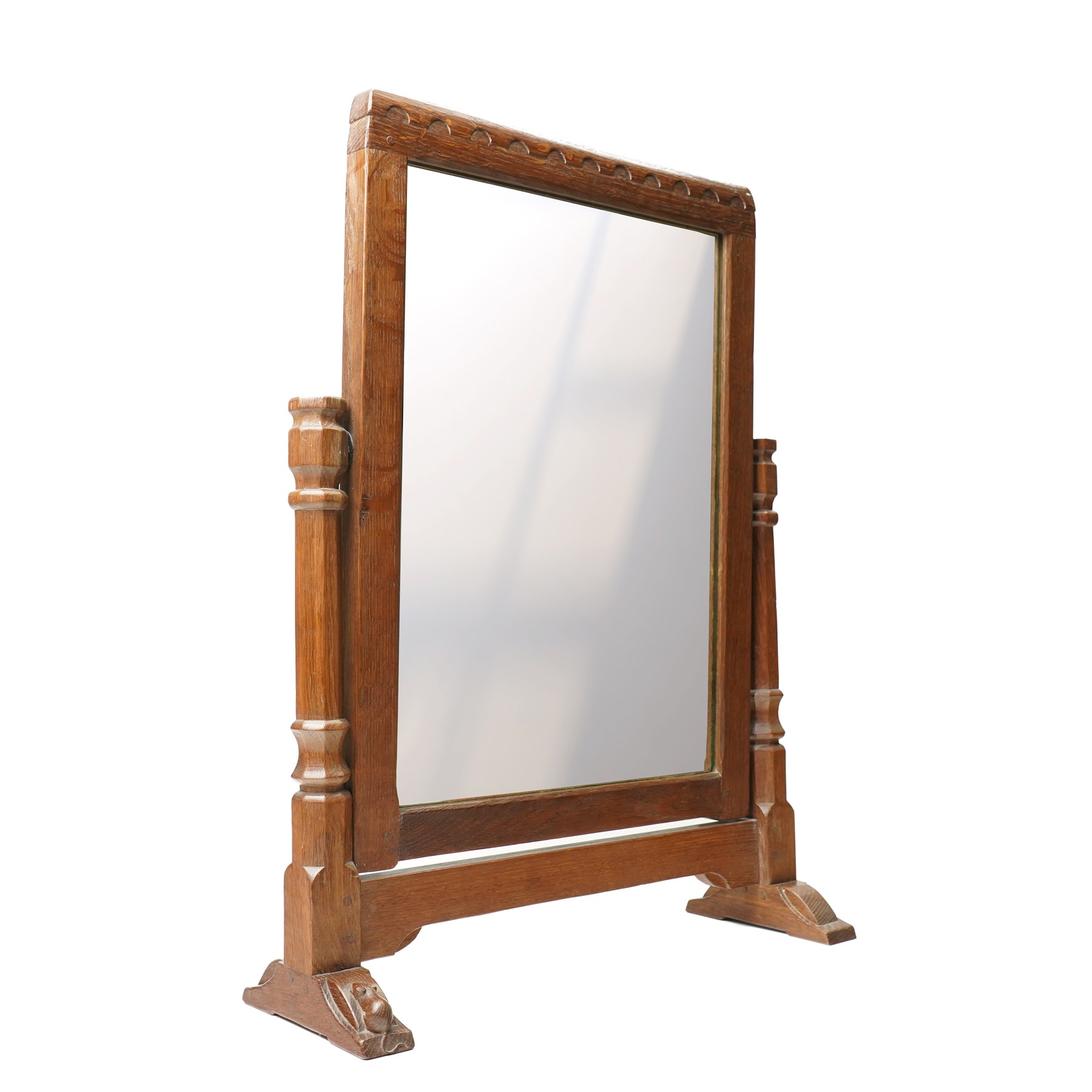 Mouseman - 1930s/40s lightly adzed dark oak dressing table swing mirror, the arcade carved cresting rail over a rectangular plate, the mirror pivots between two lappet-carved turned octagonal supports with dished tops, raised on sledge feet, with carved mouse signature, by the workshop of Robert Thompson of Kilburn