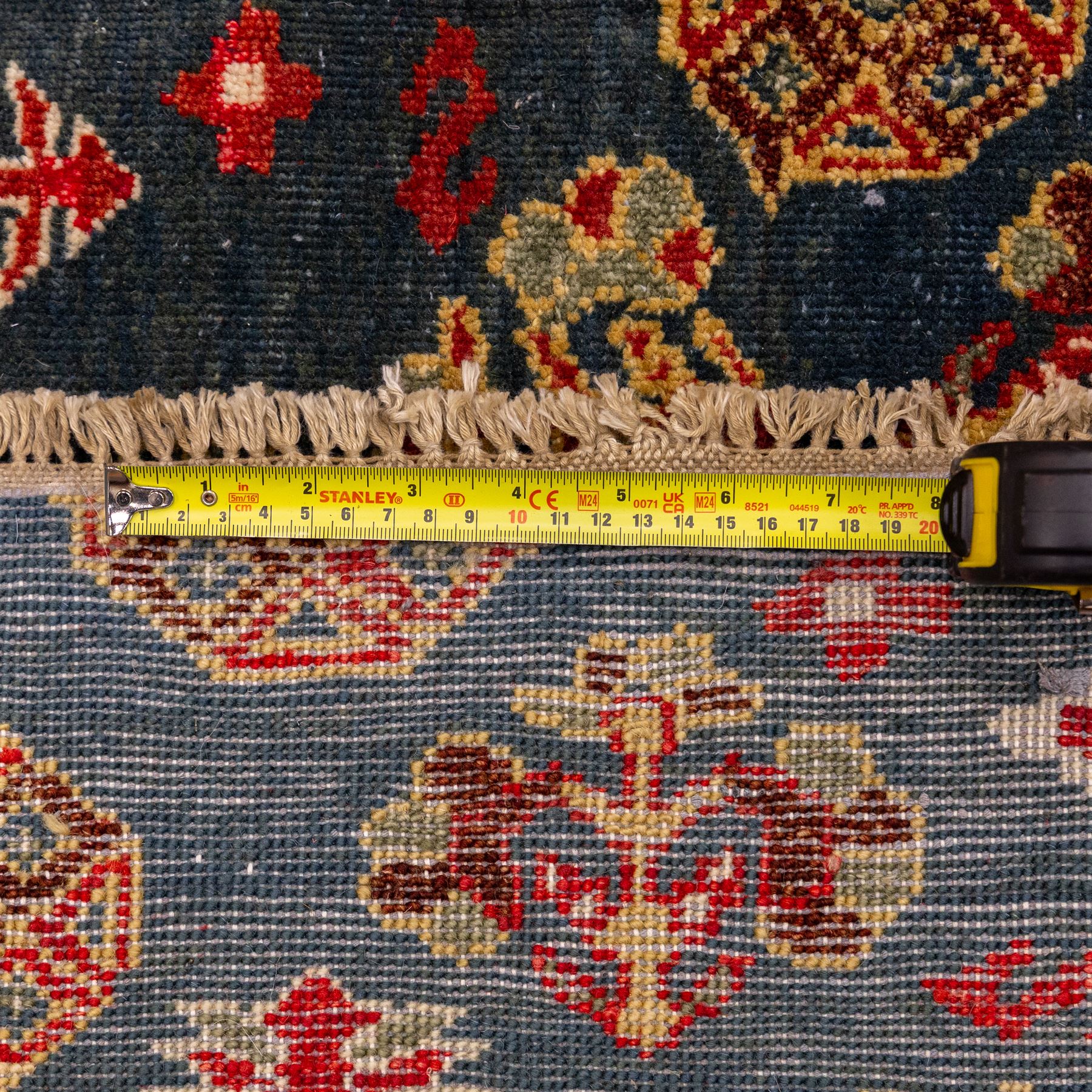 North East Persian Turkoman hand-knotted rug, deep teal blue field decorated with repeating rows of stylized octagonal guls and cruciform tribal motifs arranged in a lattice formation, enclosed composition featuring angular devices and reciprocal motifs, with cotton fringe ends