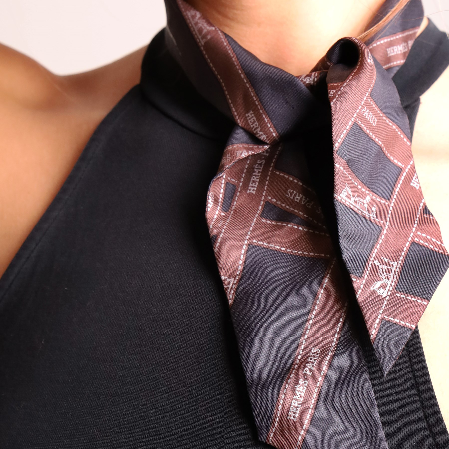 Hermès - two ‘Bolduc’ silk Twilly scarves, in orange/black and navy/brown colourways, together with three palladium-tone Médor pyramid Twilly scarf rings, with original dust bag and cylindrical box