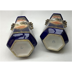 A pair of Japanese Nippon Kinjo vases, of tapering hexagonal form with twin stylised handles, the cobalt blue ground with oval hand painted panels to front and verso depicting landscapes, further detailed with smaller floral bands and panels and heightened with gilt, each with mark beneath, H30.5cm.  