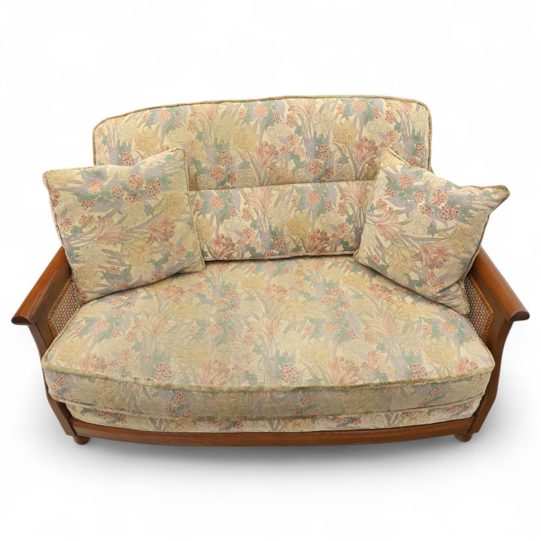 Ercol – bergère four piece suite, including armchair, two seat sofa, three seat sofa and footstool, all with removable floral upholstered cushions, the frames with side caning and rounded arm supports in stained beech

Three seat (H 87cm, D 89cm, W 196cm)
Two seat (H 87cm, D 89cm, W 137cm)
Armchair (H 87cm, D 89cm, W 87cm)
Footstool (H 28cm, D 55cm, W 55cm)