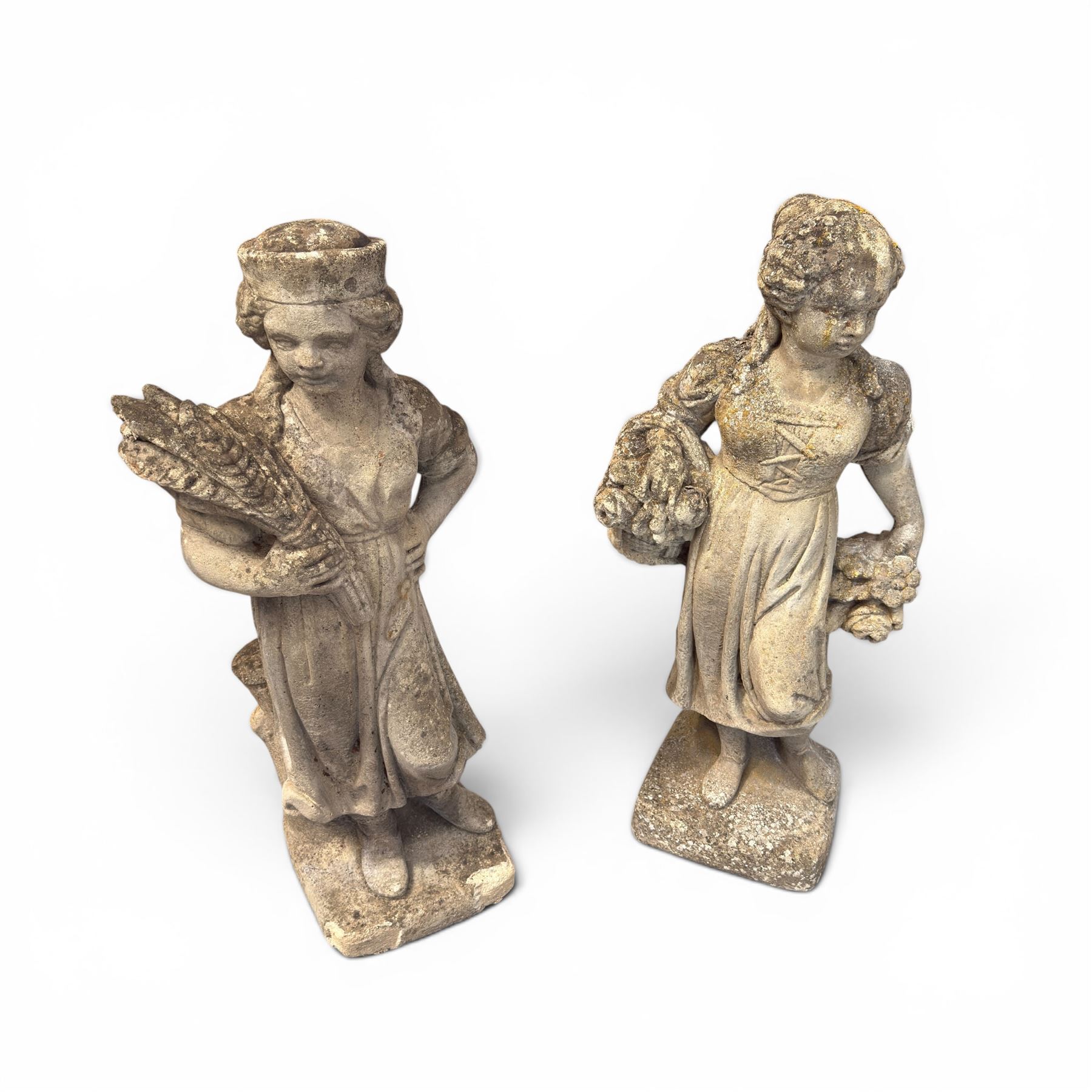 Lucas Stone - pair of cast stone garden figures, modelled as young female figures holding wheat sheafs and baskets of flowers, each on square bases, weathered finish, makers mark stamped to base