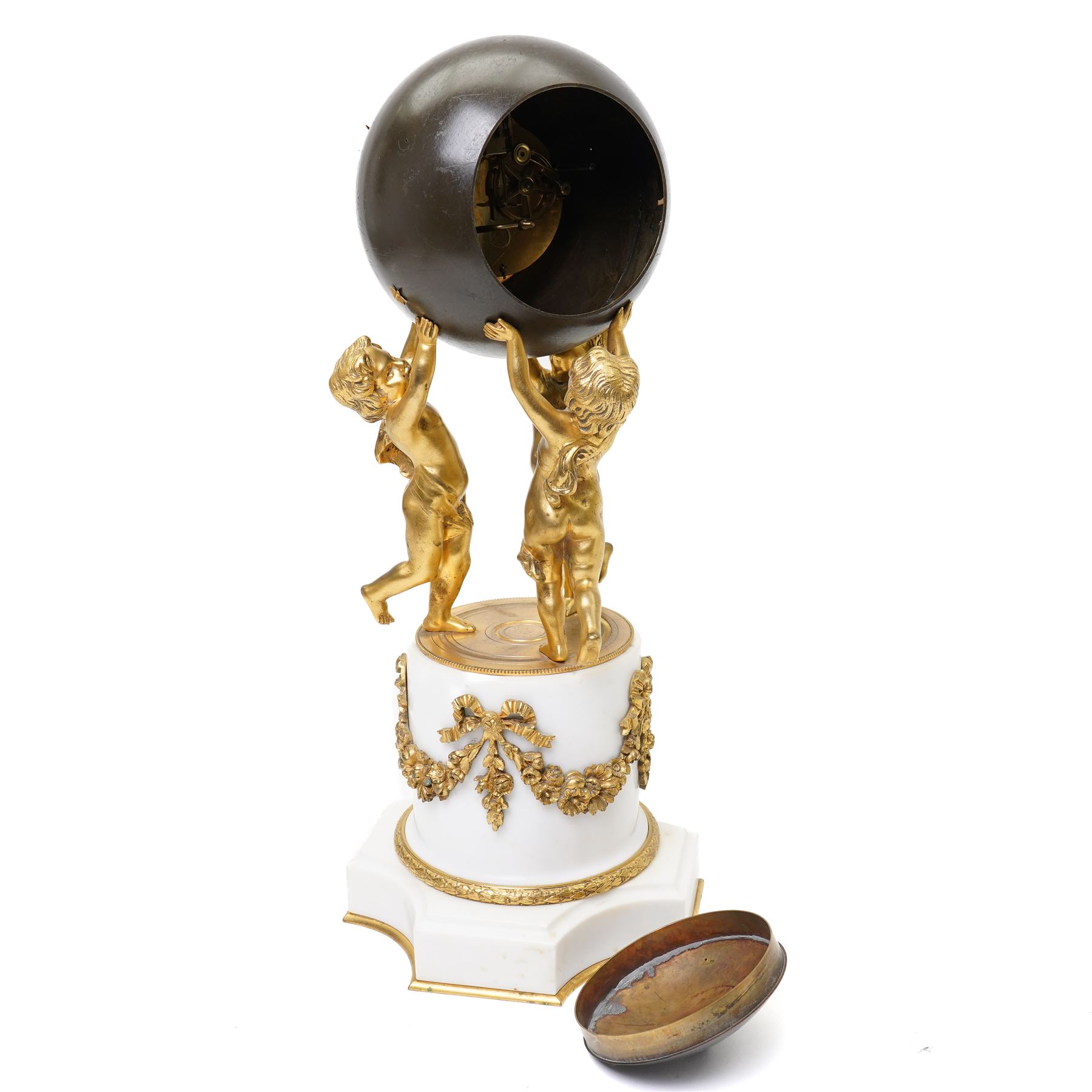 French- late 19th century 8-day globe clock, patinated globe with applied gilt Roman numerals, arrow-shaped hands and supported by three ormolu putti on a stepped columnar white marble base with a floral garland mount, twin train Parisian movement by Japy Freres with a recoil anchor escapement and countwheel strike, sounding the hours and half-hours on a bell. With pendulum.