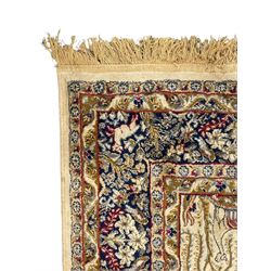 Persian Kerman ivory ground rug, the field adorned with naturalistic depictions of birds, animals and floral designs, framed by a multi-band border in blue and red tones