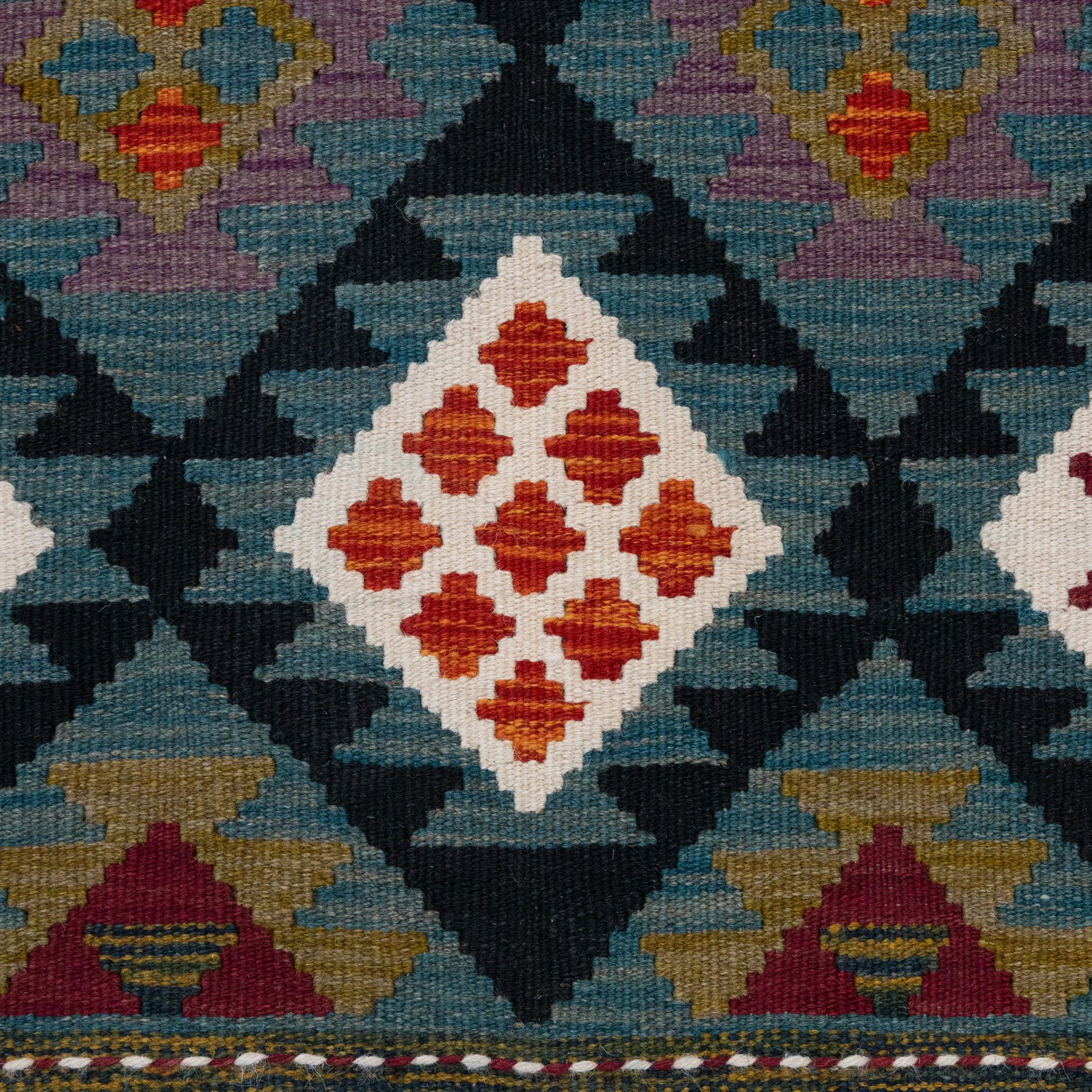 Afghan kilim teal ground runner rug, the field decorated with assorted lozenges with geometric motifs and dark indigo borders, enclosed by a narrow striped guard band