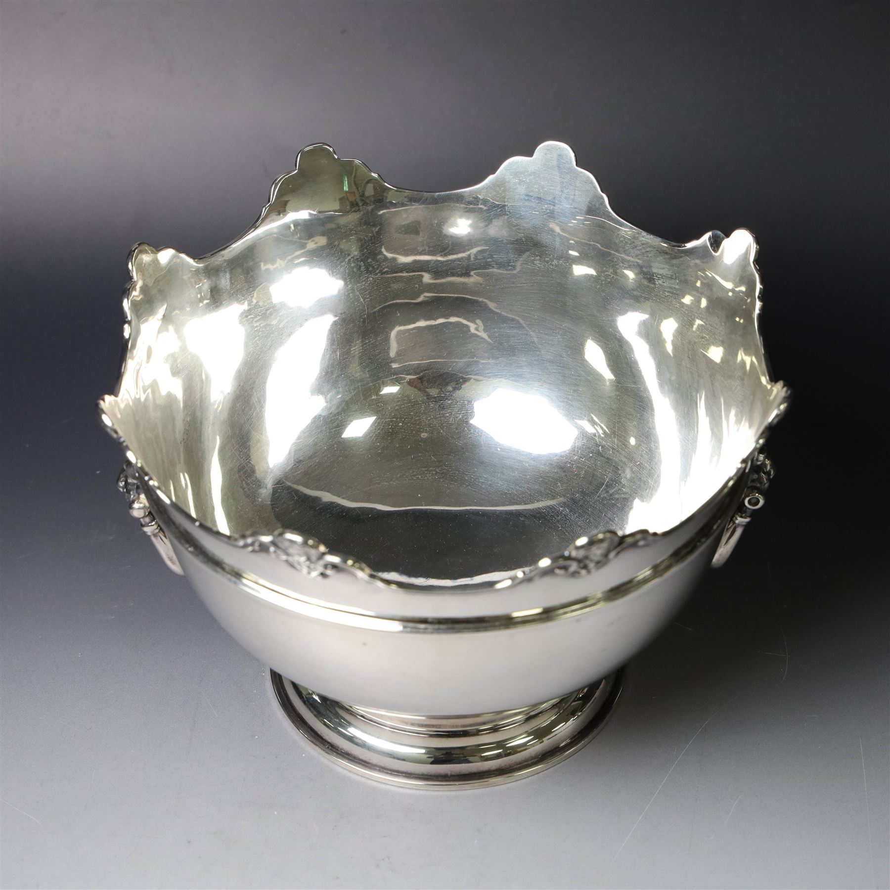 Edwardian silver Monteith punch bowl, the scalloped rim with strapwork and figural decoration, with two lion mask mounted ring handles, upon a circular stepped foot, hallmarked London 1903, maker's mark worn and indistinct, H15cm, D23cm
