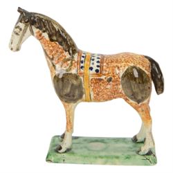 Late 18th/early 19th century Prattware pottery figure of a horse, possibly Yorkshire Potteries, circa 1790-1800, painted and sponge decorated in manganese, with blue spotted saddle secured with a yellow girth, upon a rectangular green base, H15.5cm