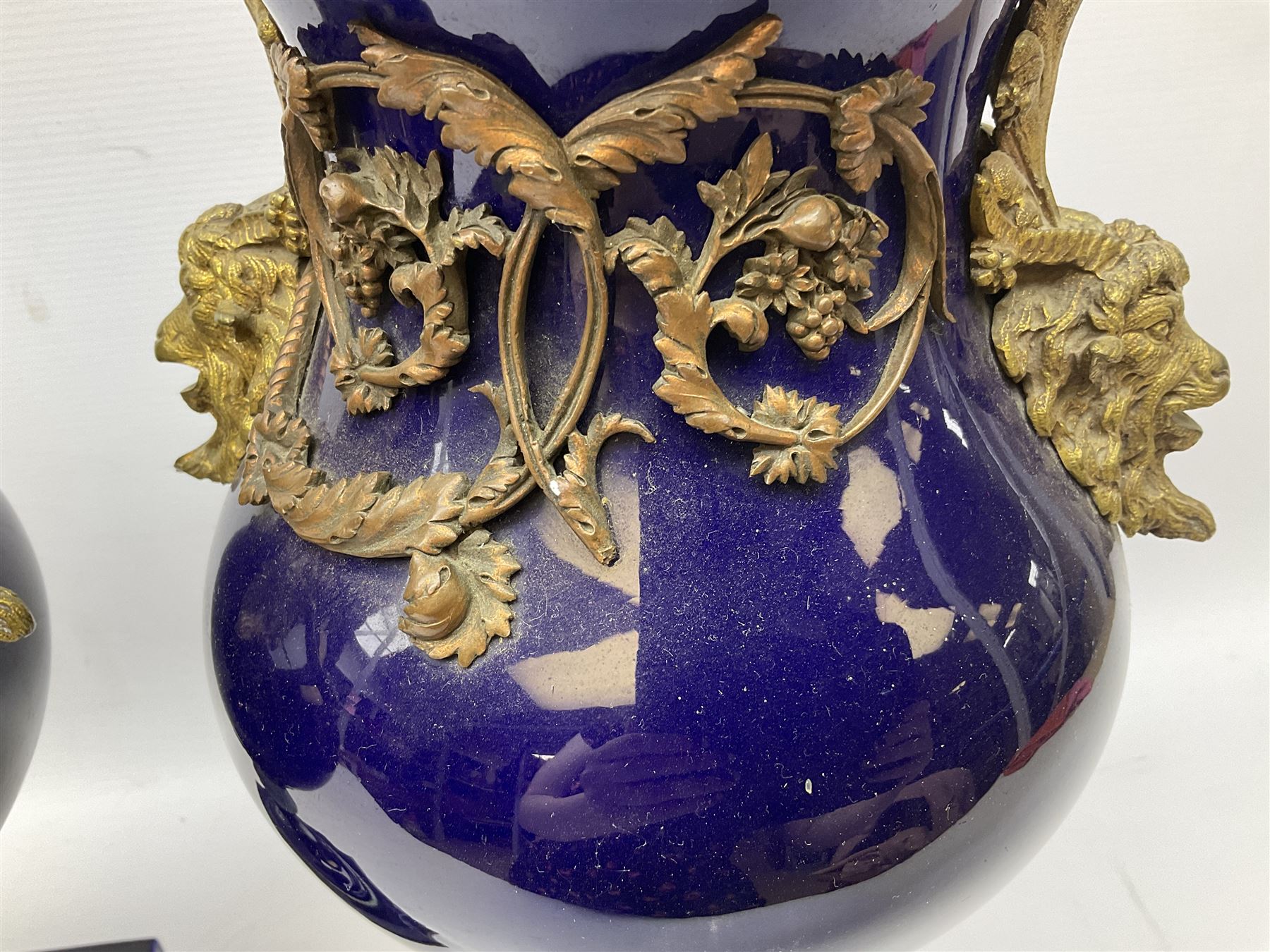 Pair of French large cobalt blue lidded urns, probably 19th century, the body decorated with ormolu ram's heads and ornate foliate design, the domed cover with brass berry finial, raised upon pedestal base with beaded decoration upon shaped plinth, H52cm