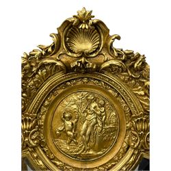 Large Italian Baroque design gilt wall mirror, the shell pediment over circular panel depicting classical female flute player with dancing putto within a tree landscape, the stepped arched upper frame surmounted by musical instrument playing putto and trailing flower heads, central bevelled mirror plate surrounded by plain segmented mirror plates, acanthus leaf moulded outer frame and foliate moulded inner slip