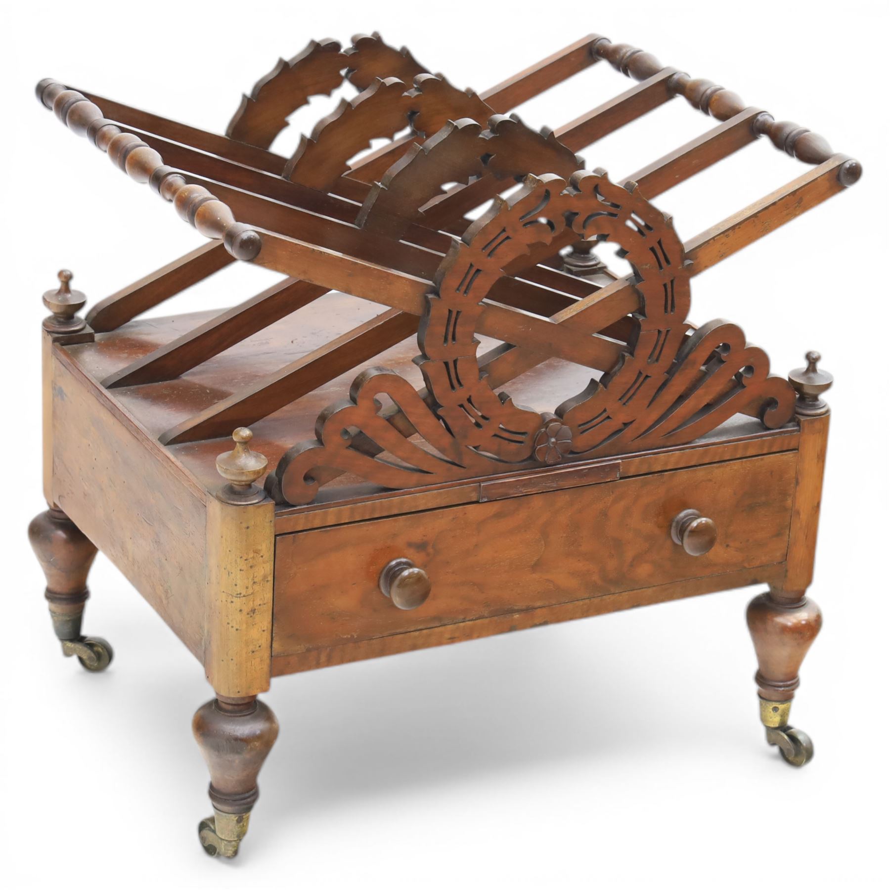 19th century mahogany music canterbury, with pierced dividers united by turned handles, above a single frieze drawer, raised upon baluster supports on brass castors