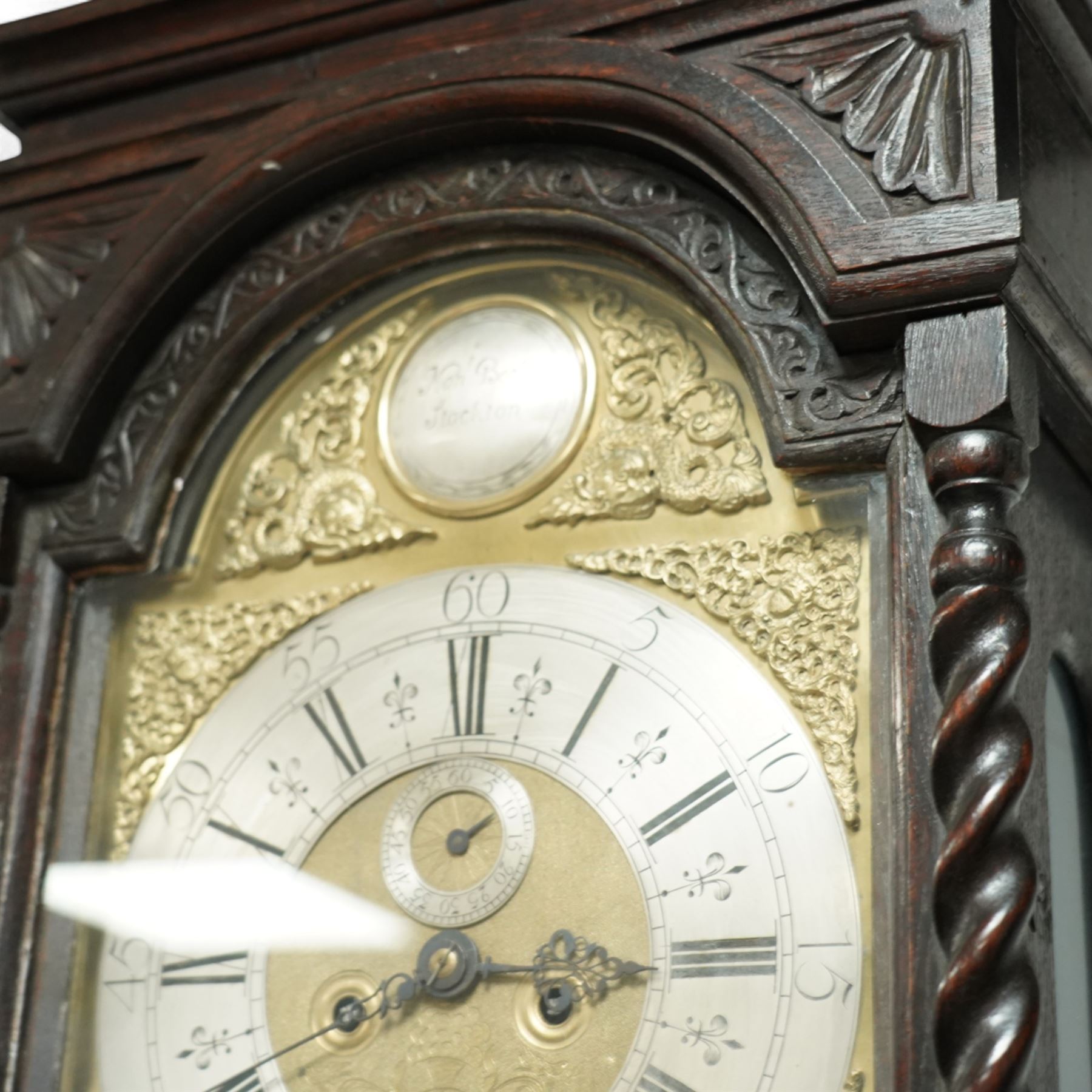 Man Beckett (I) of Stockton on Tees (Co Durham) - 8-day early 18th  century longcase clock in a  profusely carved oak case, with a caddy top, turned finials and attached barley twist pilasters to the break arch hood door, long trunk with carving and a conforming long rectangular door carved with a Celtic depiction of the tree of life, corresponding plinth with a carved and decorative base, break arch brass dial with a rounded brass surround, cast spandrels and silvered boss with the makers name to the arch, matted dial centre with seconds dial, ringed winding apertures, square date aperture and fettled steel hands, silvered chapter with Roman numerals, five minute Arabic's, half hour markers, minute and inner quarter hour tracks, dial pinned to a five pillar movement with inside countwheel striking and a recoil anchor escapement, striking the hours on a bell. With weights and pendulum.
Man Beckett (I), (first name is a biblical name short for Manasseh), was the first member of the Beckett family of prodigious clockmakers working in the North-East of England from 1720 until 1884.