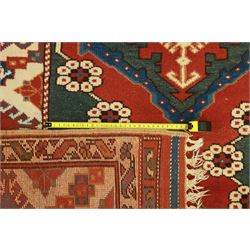 Caucasian Soumak rug, red madder field and teal panels, with bold stepped diamond medallion with hooked motifs and cruciform devices, and floral rosette clusters, surrounded by an ivory border with large hooked diamonds and stylized ram's horn devices, flanked by narrow guard stripes




