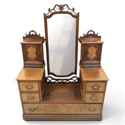 Edwardian figured walnut dressing chest, with central tilting mirror with pierced fret work, flanked by cabinet with figured walnut panelled door above a trinket drawer, with four short over a long long drawer, raised on a plinth base with castors 