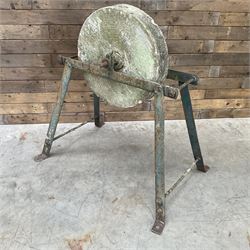 Vintage grindstone sharpening wheel mounted on metal stand, and a cast iron water pump