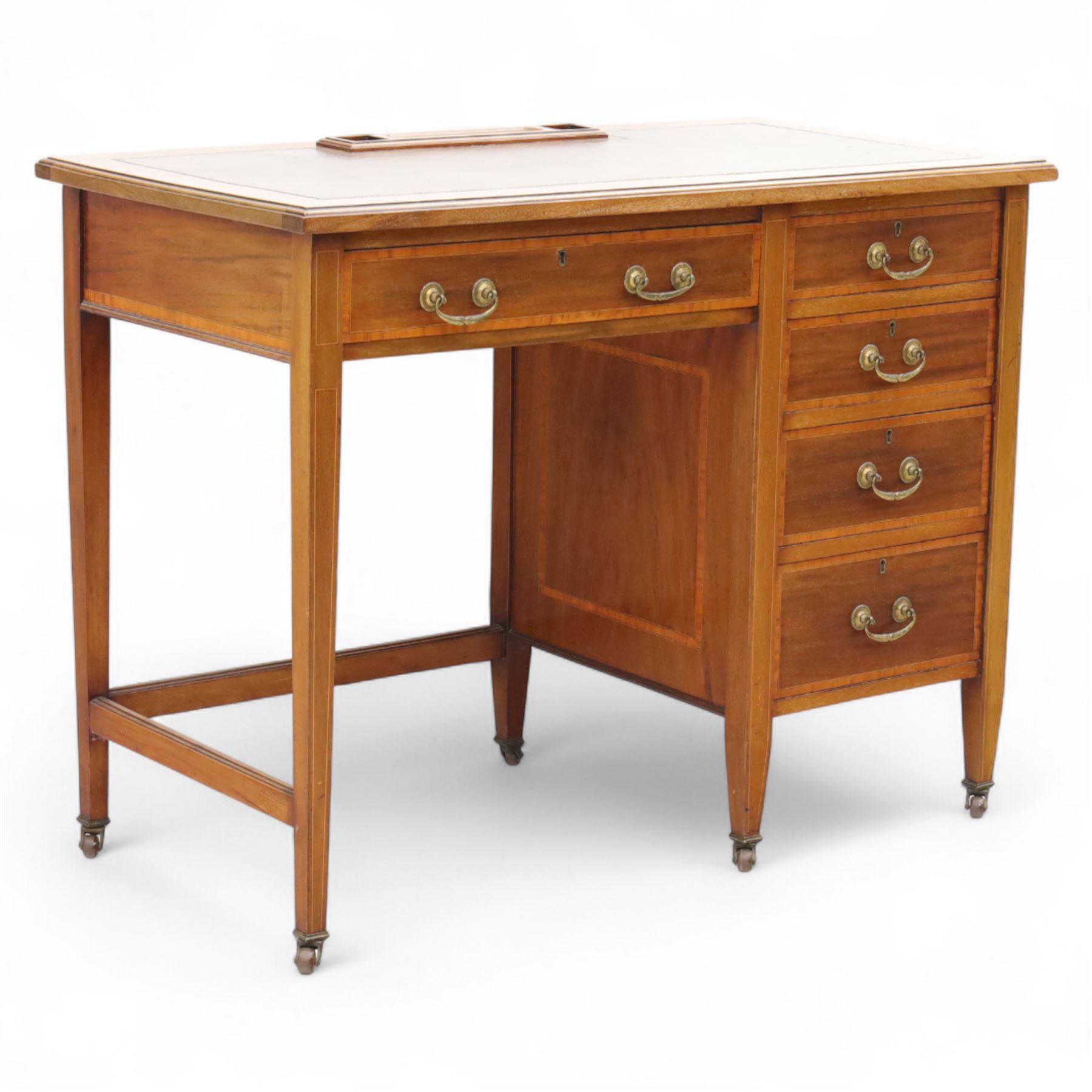 Early 20th century Edwardian mahogany single pedestal writing desk, the crossbanded rectangular top inset with brown leather, fitted with five drawers with brass swan neck handles, upon square tapering supports terminating in brass castors