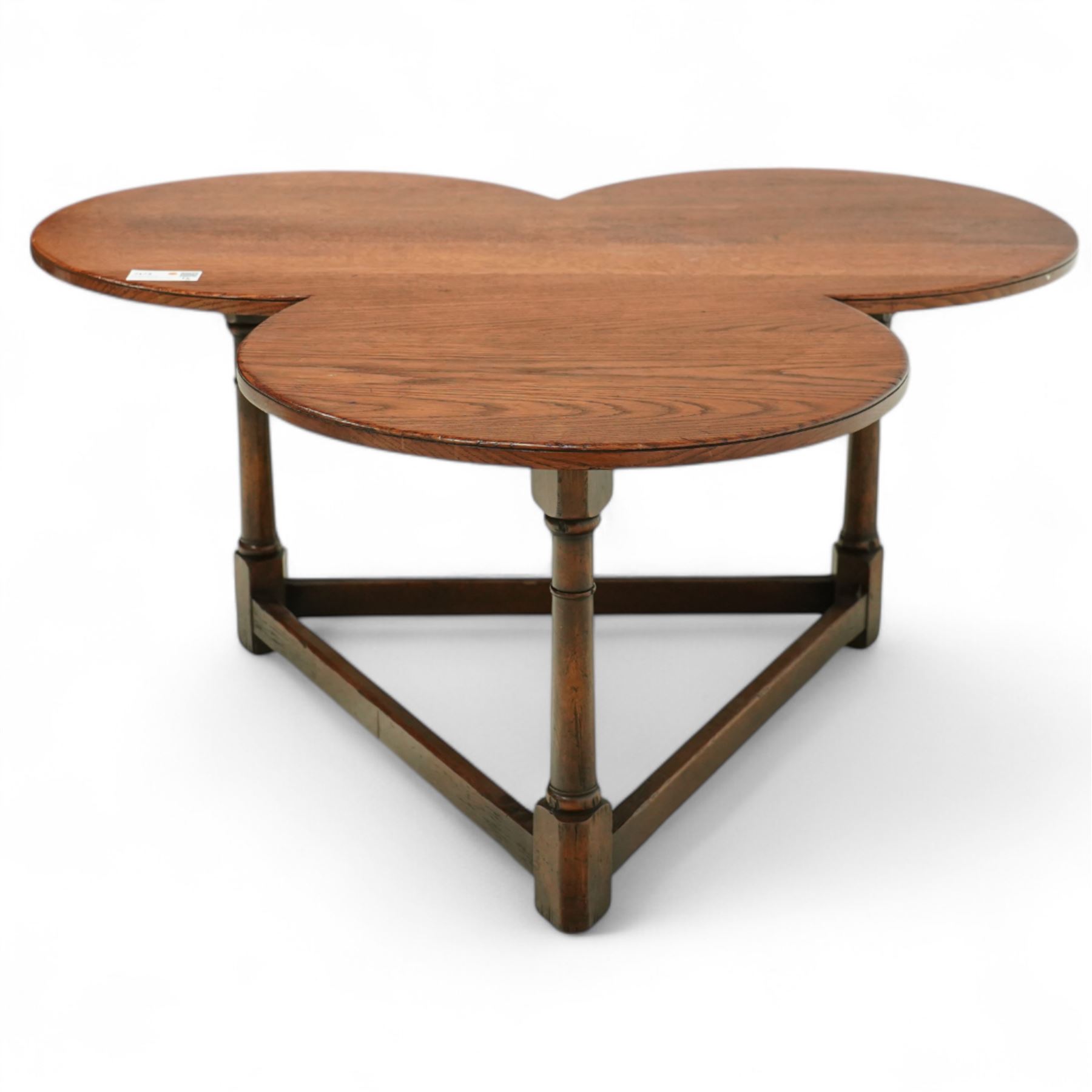 Mid 20th century oak trefoil shaped coffee table on ring turned supports joined by stretchers terminating in square feet 