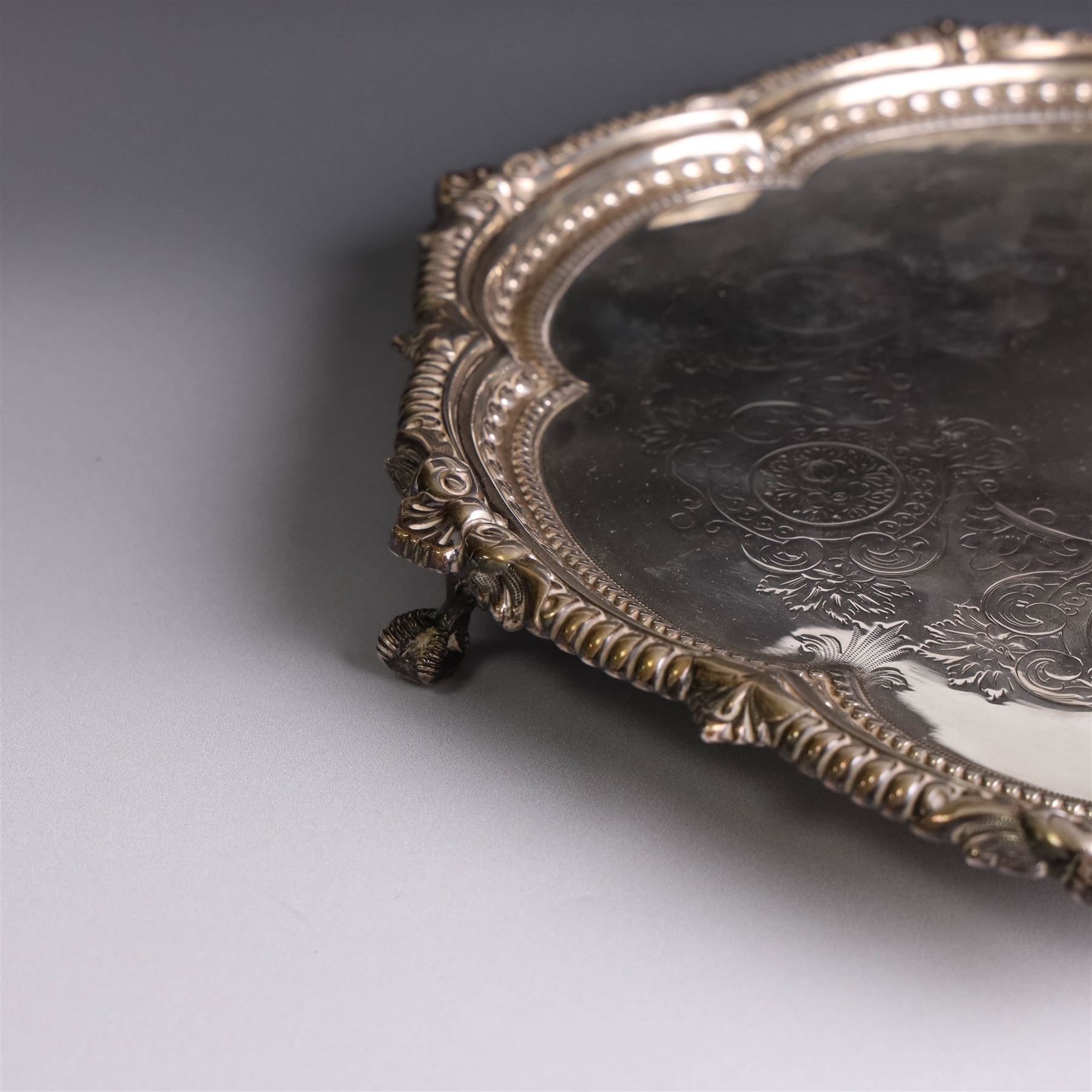 Late Victorian silver salver, of lobed circular form, with foliate beaded rim and engraved floral decoration to centre, upon three claw and ball feet, hallmarked Martin, Hall & Co Sheffield 1896, D26cm