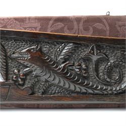 17th century walnut frieze, or pediment, carved with a smiling mans faced flanked my two creatures, incised date 1617, mounted on fabric panel, W52cm