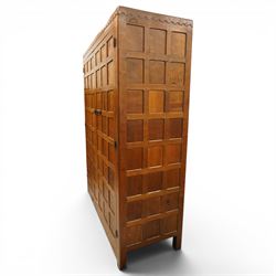 Mouseman - early-to-mid-20th century figured panelled and adzed double wardrobe of large proportions, the arcade carved cresting rail over two doors with adzed and figured oak panels, with wrought metal hinges and latch, relief carved mouse signature, the interior fitted with hanging rail, by the workshop of Robert Thompson, Kilburn