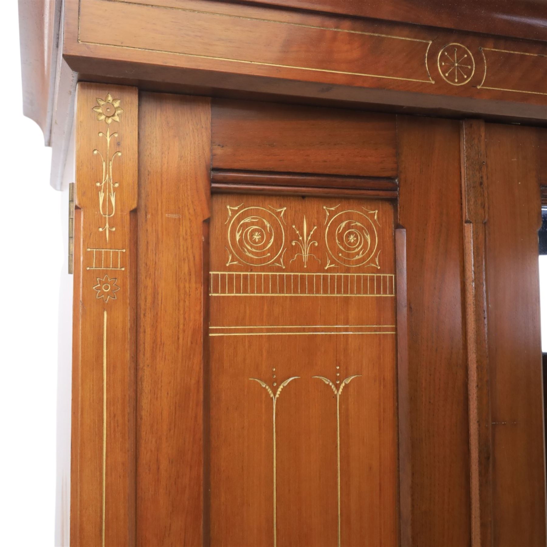 Aesthetic Movement walnut parcel gilt wardrobe, the crenellated top, above central mirrored door opening to reveal hanging space, four opened and two closed draws