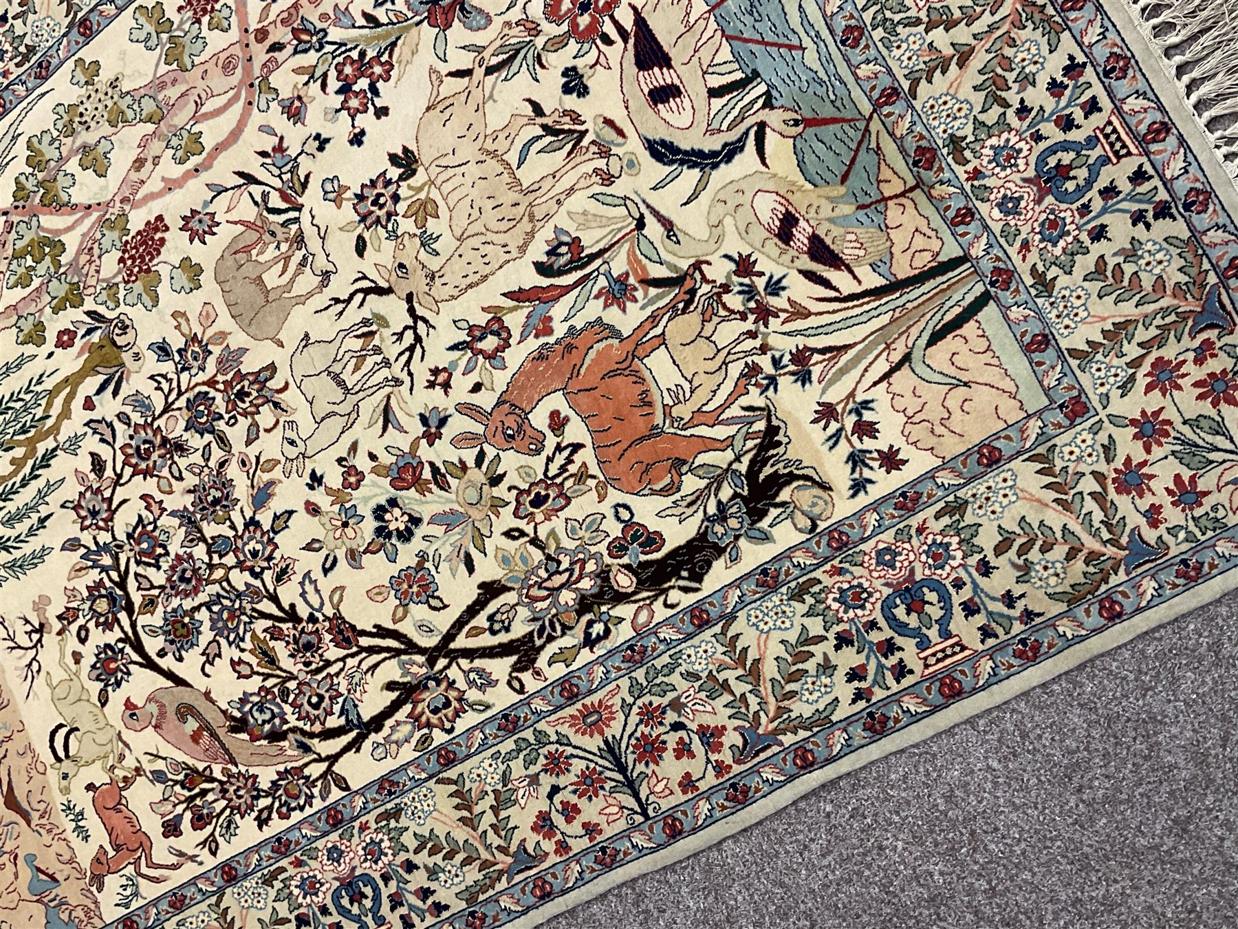 Fine Persian tree of life rug wall hanging, ivory ground field depicting landscape filled with animals, birds and flowers, the guarded border with stylised flower heads and foliage decoration, with brass hanging rail