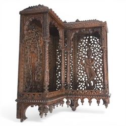 20th century Indian carved hardwood corner shelf, the tiered pagoda form with pierced and carved foliate panels centred by figural carving, supported by turned and carved columns, with shaped brackets and pendant finials