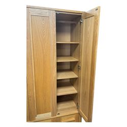Contemporary light oak triple wardrobe, panelled doors with vertical linear design, left section enclosing hanging rail and single shelf, right section with adjustable shelves, over two drawers, on square stile supports