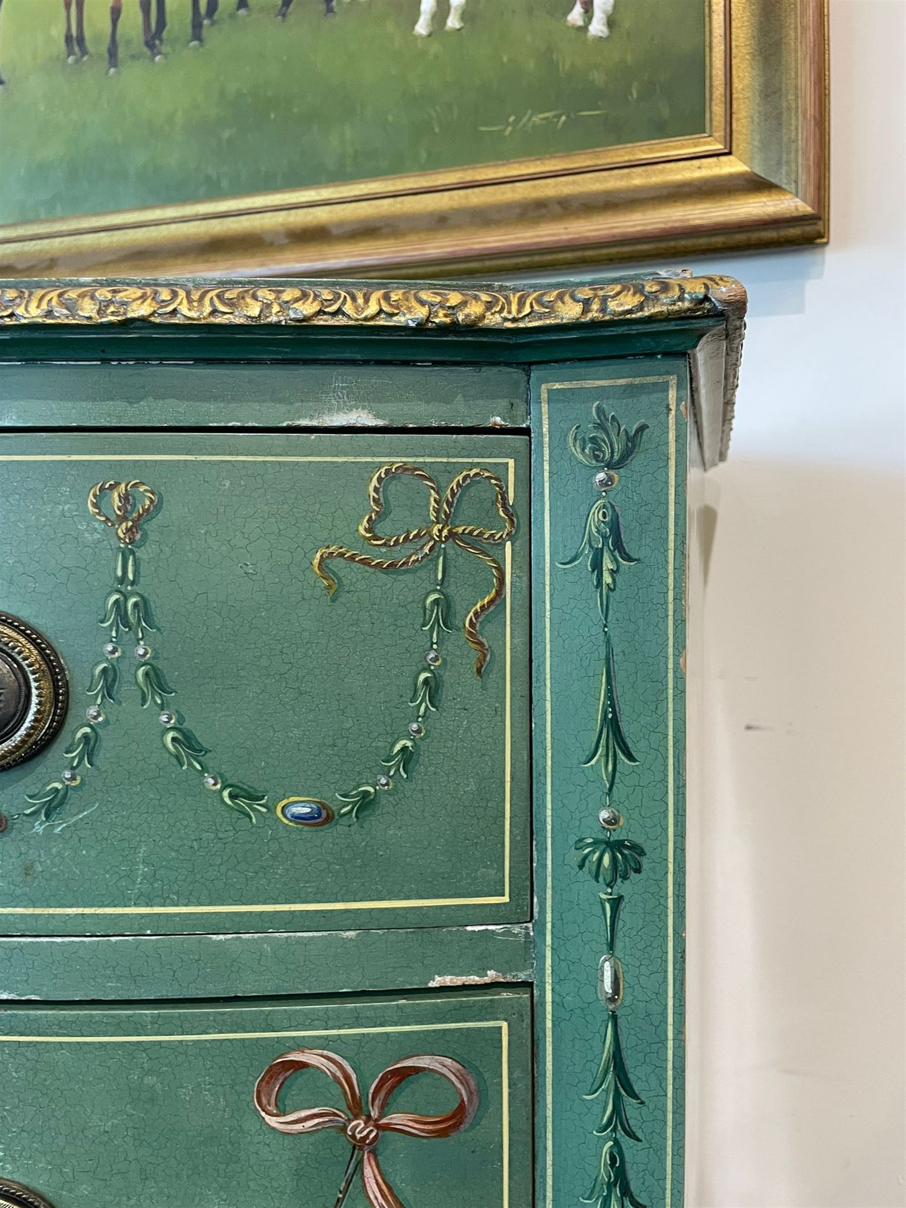 Edwardian Adam Revival green-painted and parcel gilt bowfront chest, moulded and foliate carved top painted with trailing floral band, fitted with four drawers decorated with trailing floral festoons, ribbon ties and urns, oval handle plates with engraved decoration and bead cast handles, on turned supports decorated with acanthus leaves and draped festoons 