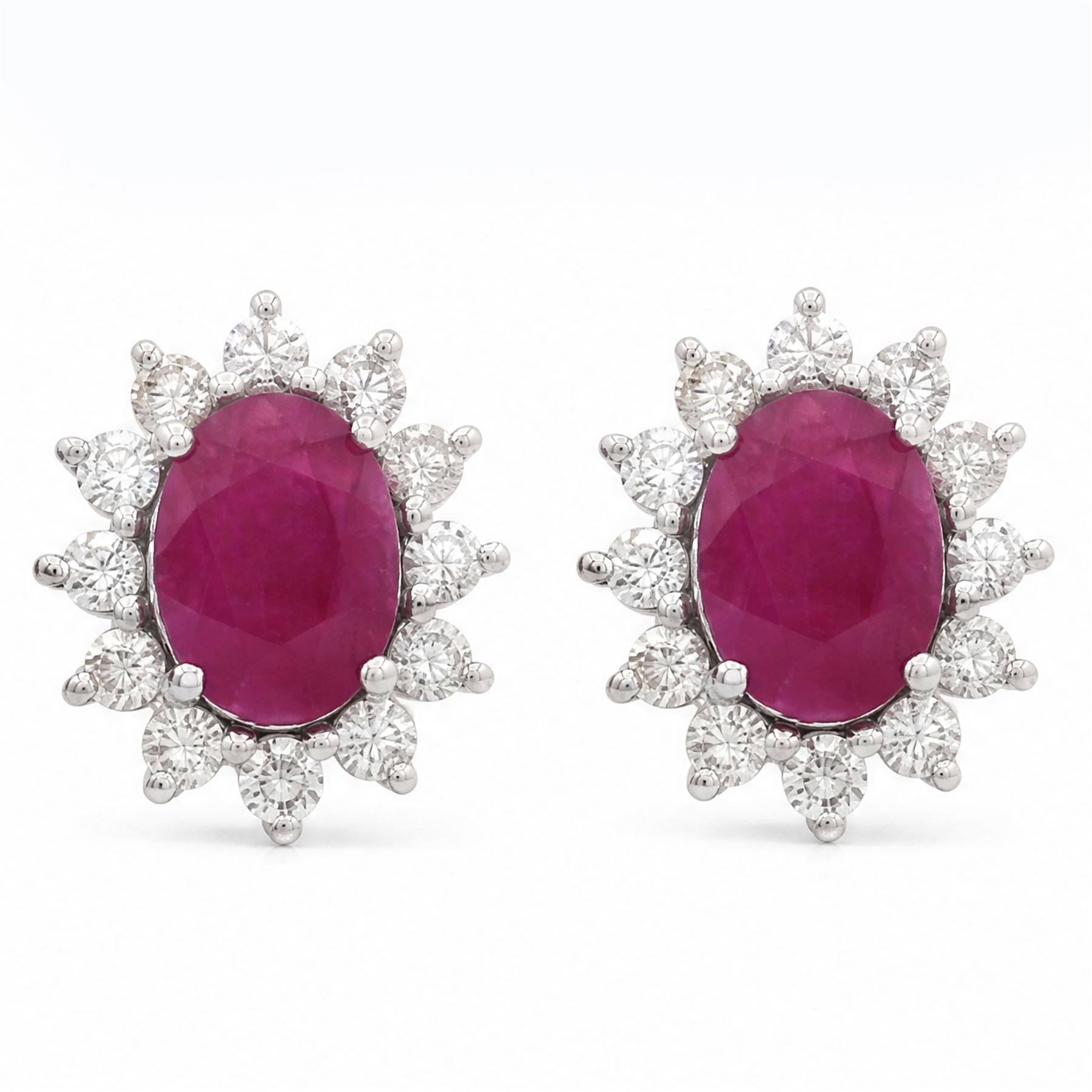 Pair of 18ct white gold ruby and diamond cluster earrings, each stud set with a single oval cut ruby and twelve round brilliant cut diamonds, stamped 750, total ruby weight approx 2.70 carat, total diamond weight approx 0.80 carat