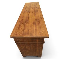 Indigo Furniture - large rustic oak sideboard fitted, with three drawers above three central drawers, flanked by fielded panelled doors, raised on bracket feet