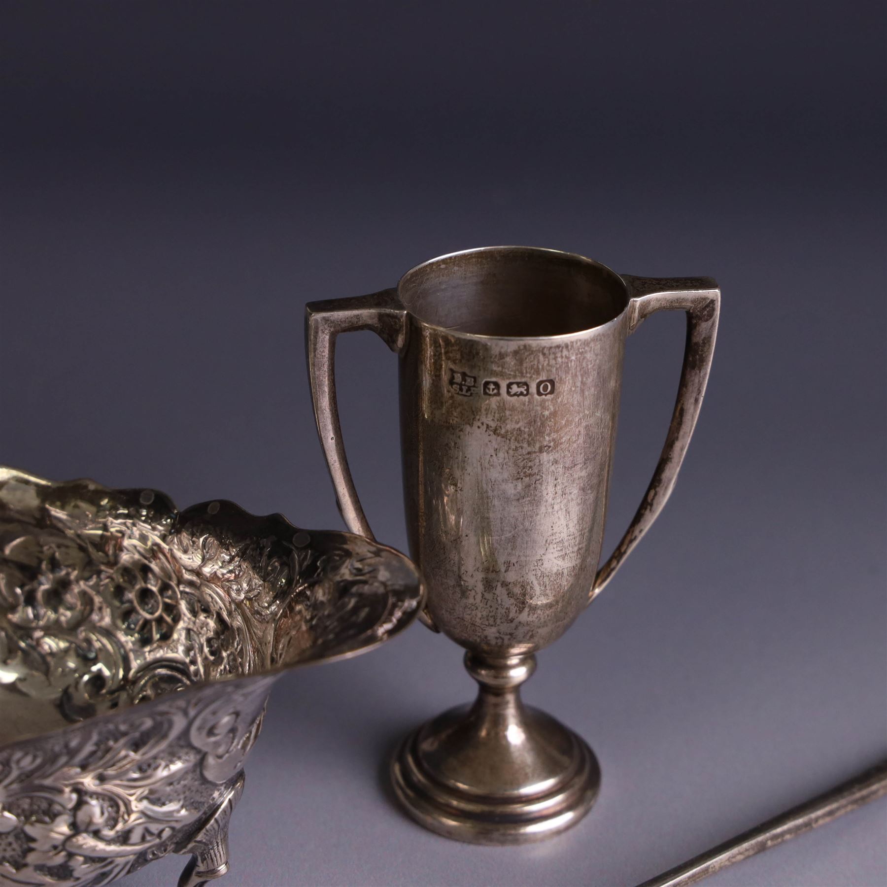Victorian silver sauceboat, of typical form with embossed floral and foliate decoration, hallmarked London 1886, together with a miniature silver trophy and silver pickle fork, both hallmarked, trophy H7.5cm