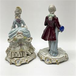 Two Capodimonte figures, the first example modelled as woman with 'lace' skirt holding a basket on a scalloped plinth, the second modelled as a man with 'lace' cuffs and ruffle holding a hat and cane on a scalloped plinth. 
