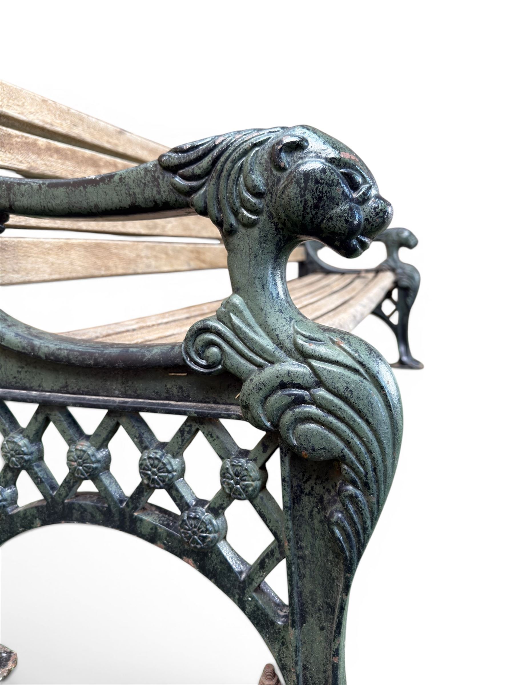 Neoclassical design cast iron and oak slatted garden bench, the twin end supports in the form of a Sphinx with acanthus carved knees and large paw feet, the pierced lattice bracket with Yorkshire rose motifs