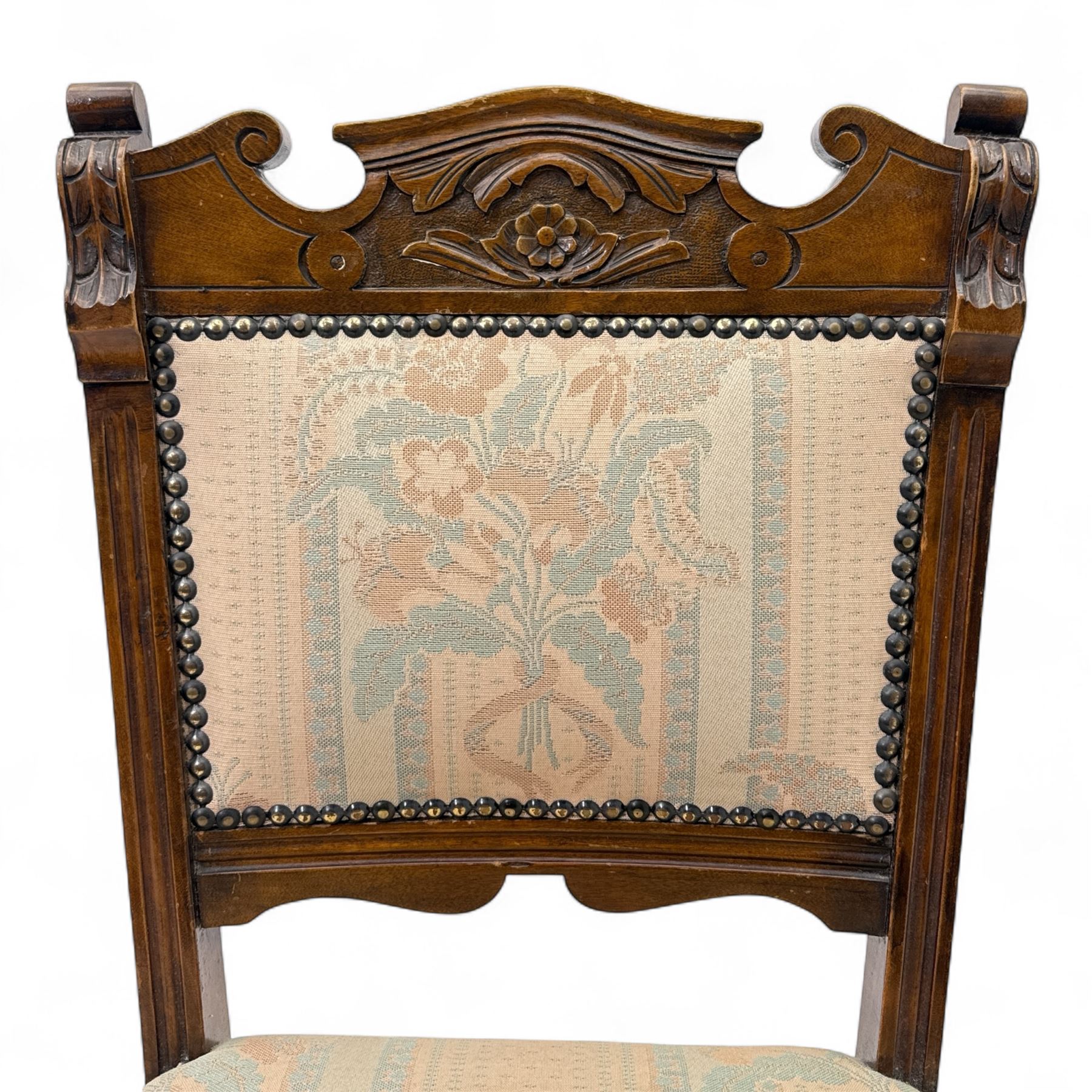 Victorian walnut set of four dining chairs, the shaped and carved top rails with central flowerhead and scroll decoration above upholstered backs and seats in floral woven fabric, brass stud trim, on ring turned front supports
