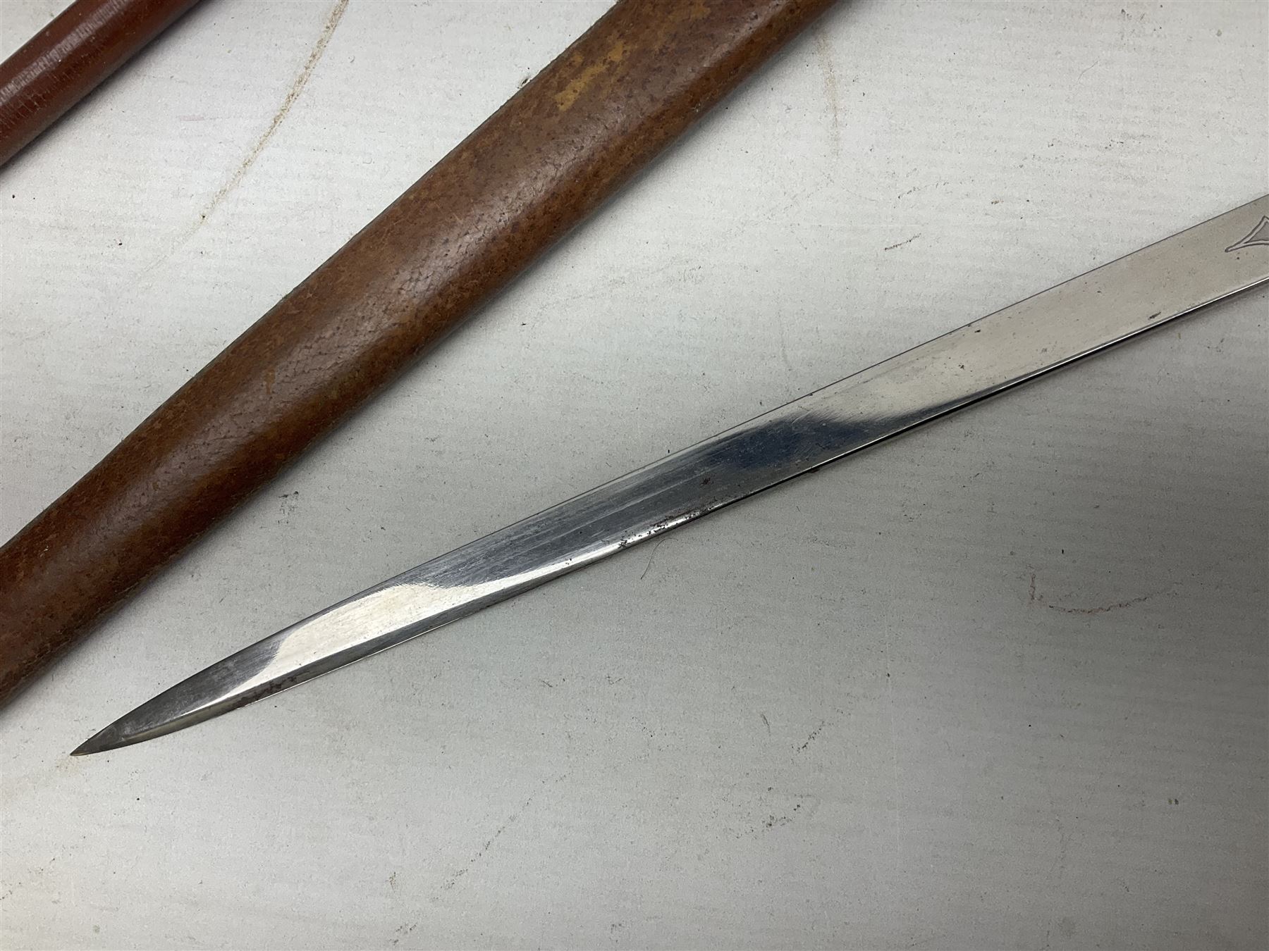 George V 1897 pattern Army Officer's sword by Henry Wilkinson Pall Mall London, the 82.5cm 'London Made' blade etched to both sides with Royal Crests and cyphers etc, pierced half-basket hilt with wire-bound fish skin grip and remains of leather knot strap; in leather covered field service scabbard L101cm overall; and two 14th Prince of Wales Own swagger sticks (3)