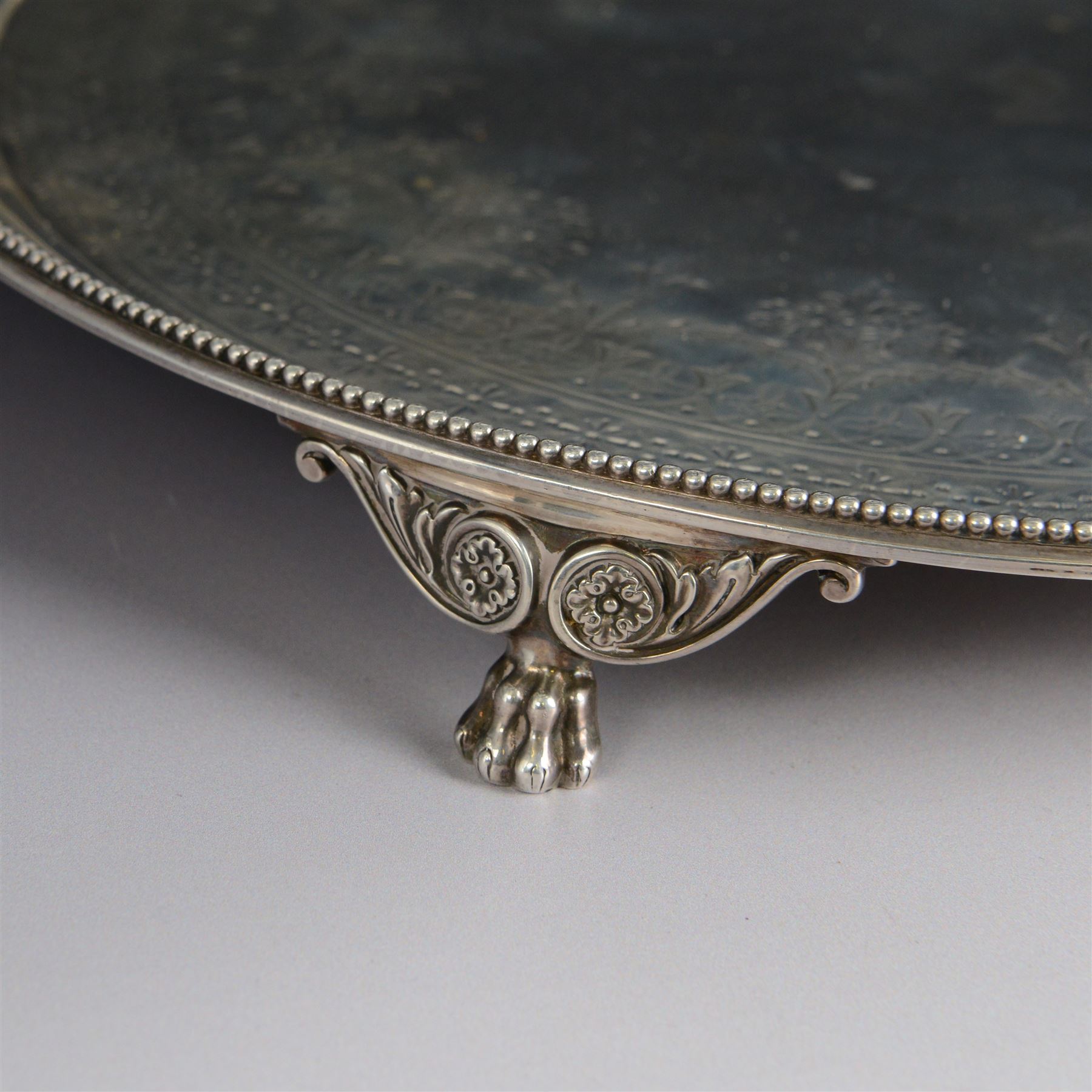 Victorian silver tray, of circular form with beaded rim, engraved to the centre with floral decoration, upon three scroll mounted paw feet, hallmarked Walter & John Barnard, London 1877, D30.5cm