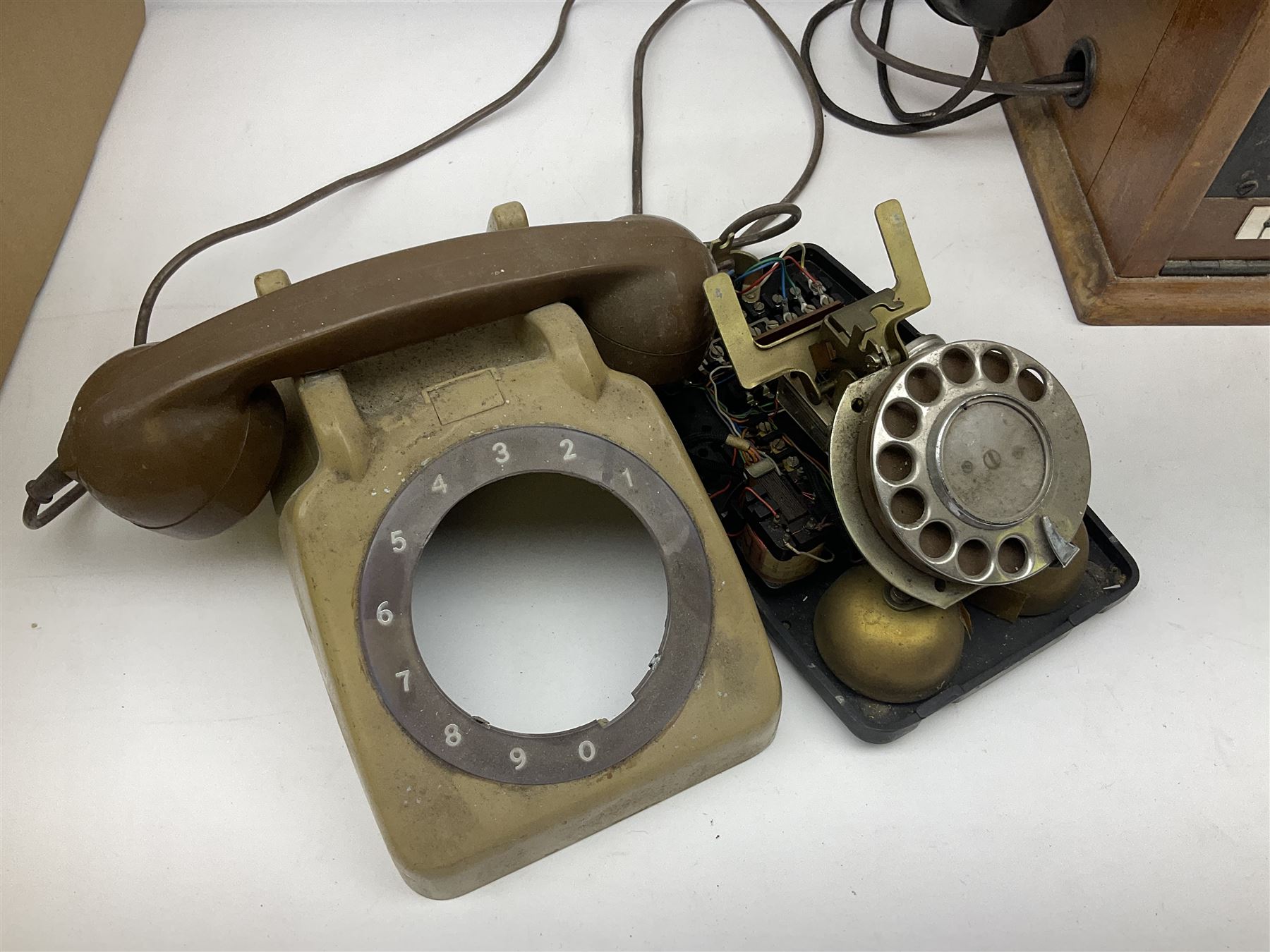 Early-mid 20th century internal telephone system, comprising exchange box with attached TMC rotary telephone and dictograph with Bakelite handset and support upon stained wood case, and 1960s black Bakelite telephone model 312L with G.P.O sticker beneath, largest H30.5cm W36.5cm D30cm