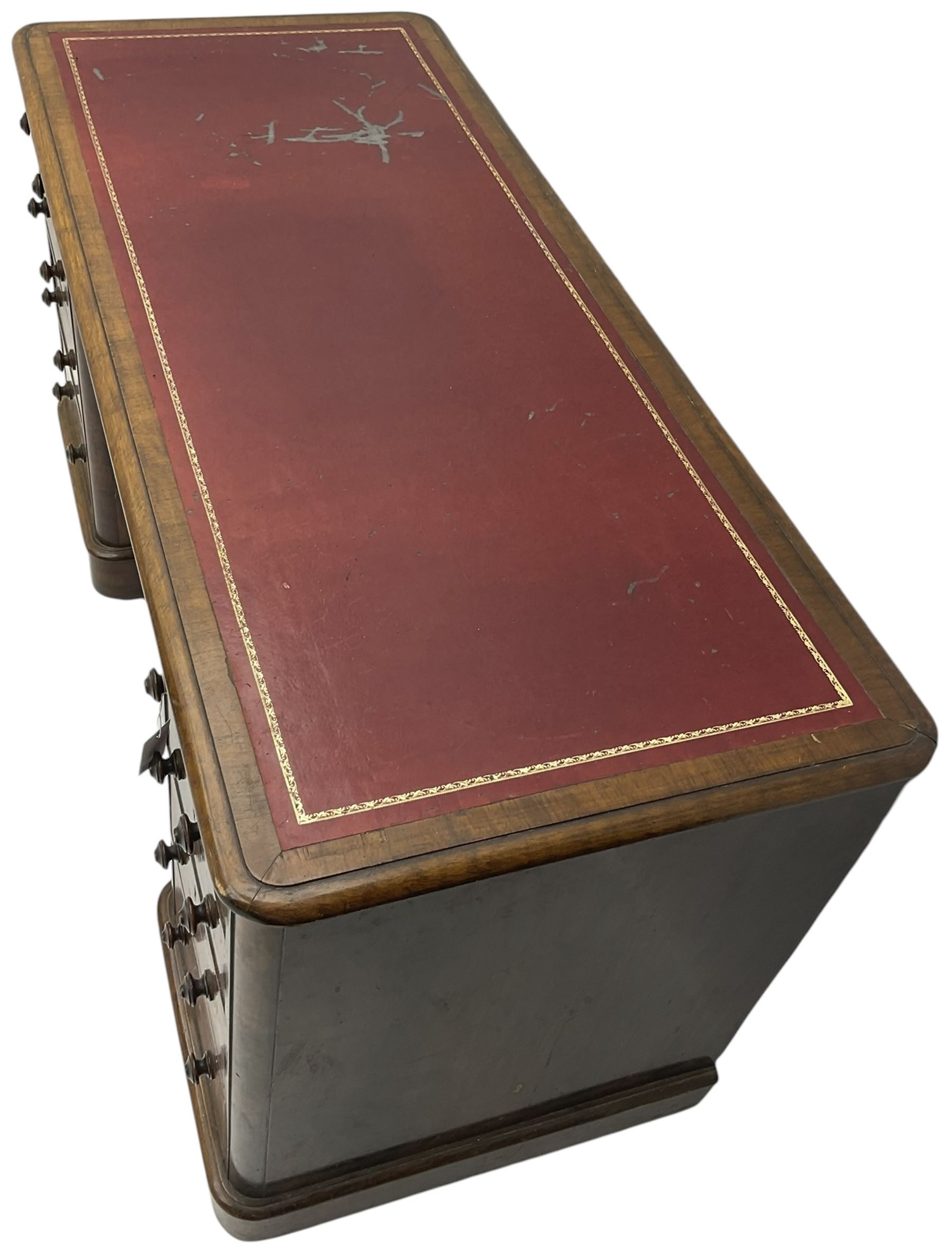 Victorian figured walnut kneehole desk, moulded rectangular top with inset leather writing surface, fitted with nine drawers, the central frieze drawer with carved curled foliage mount, on moulded plinth base,