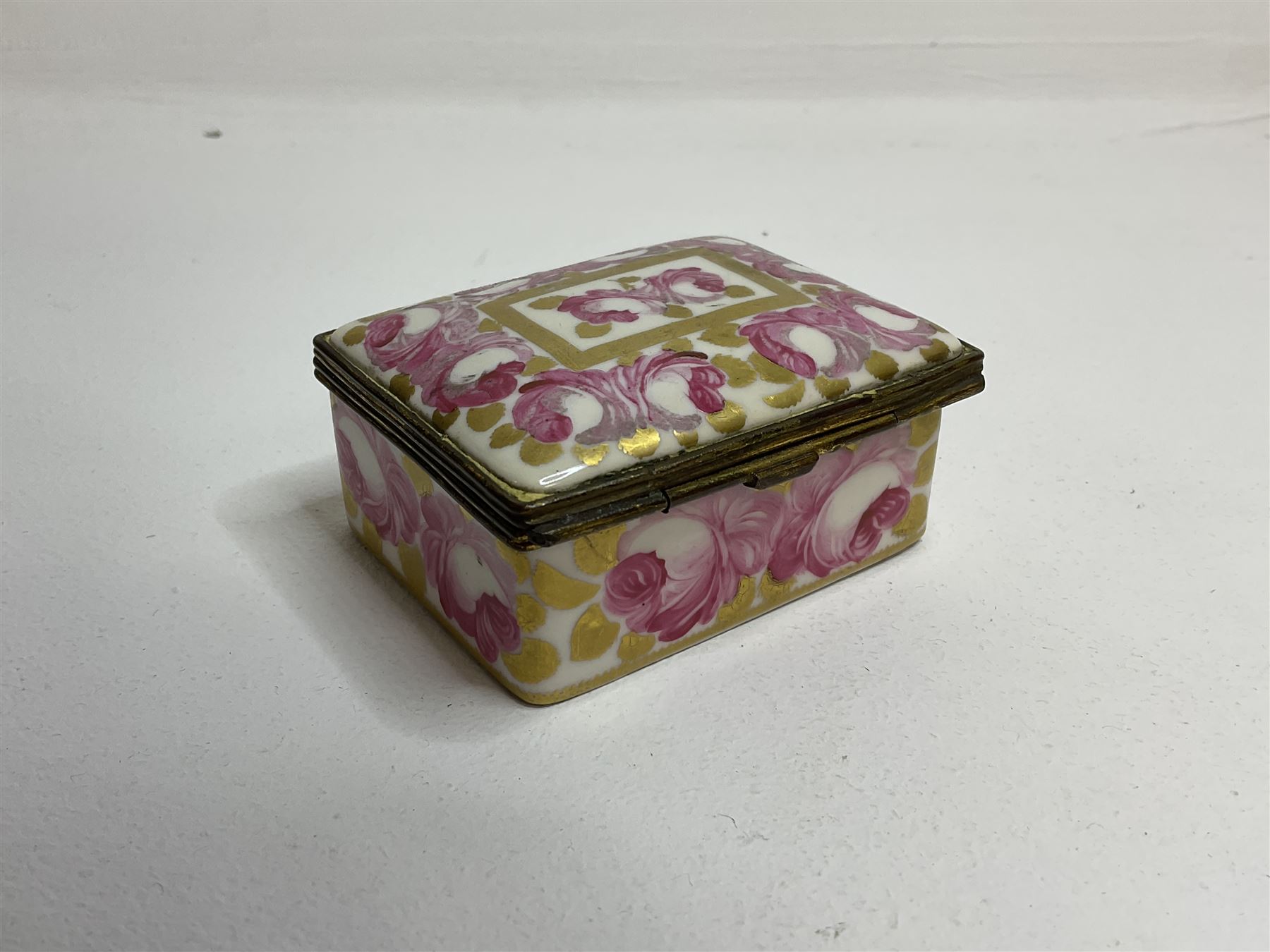 Early 19th century Swansea box of rectangular form, densely decorated with painted pink cabbage roses and gilt foliage upon plain ground, the hinged lid opening to reveal interior painted with two further roses upon plain ground, marked Swansea. in gilded lettering beneath, W7cm H3.5cm D5.5cm