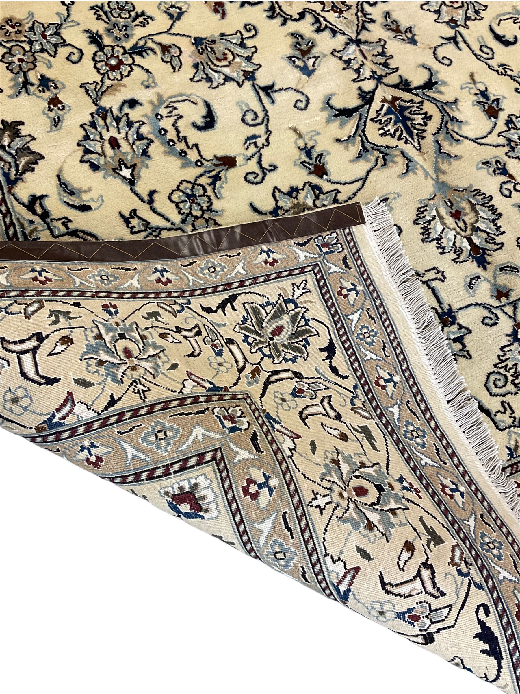 Central Persian Nain rug, wool with silk inlay, ivory ground decorated with scrolling and interlaced branch with stylised plant motifs, central floral medallion, triple band border with repeating design